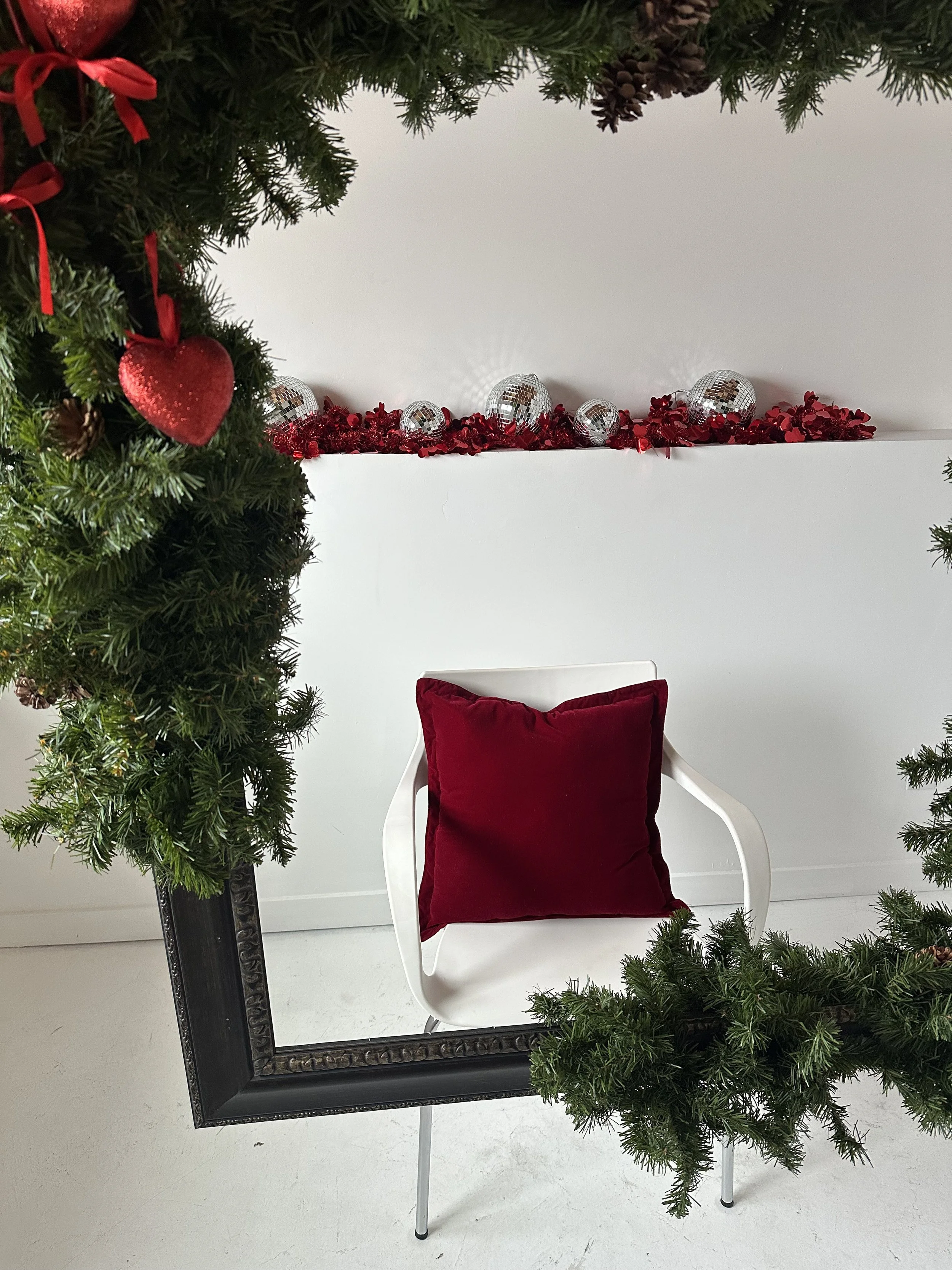 Editorial Valentine’s photoshoot background in an Edmonton studio featuring layered garland, festive red accents, and neutral styling.