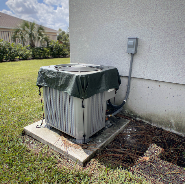 tarp strapped over outdoor AC condenser before storm
