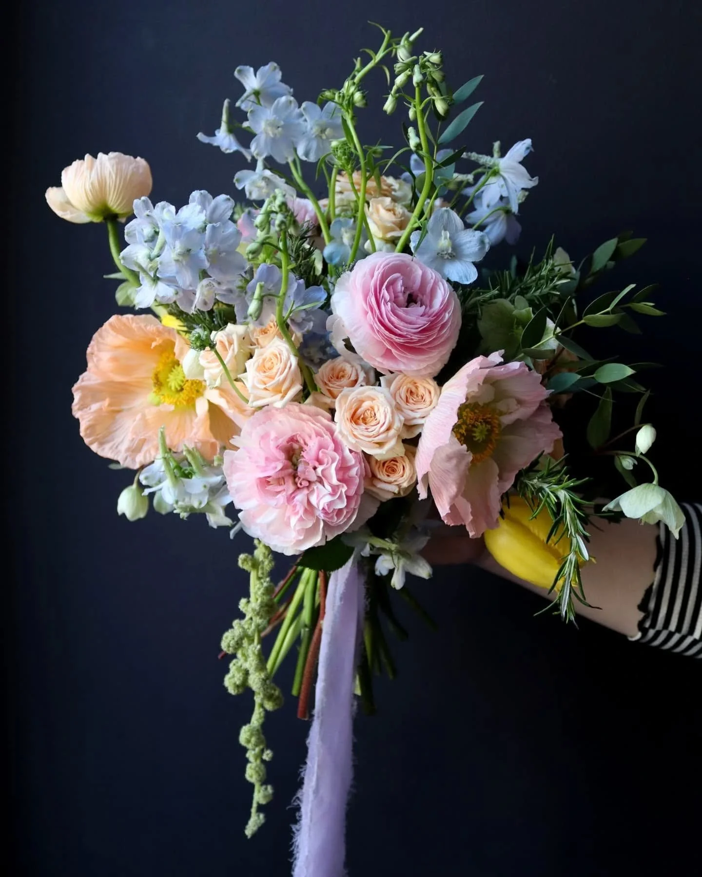 A wedding bouquet inspired by fairies. ✨

Lots of poppies, ranunculus, rosemary, delphinium and spray roses. A pretty pastel pink, blue and orange colour palette, finished with a whimsical lilac ribbon. 

#FloralArt #WeddingFlorist #Fairycore #Spring