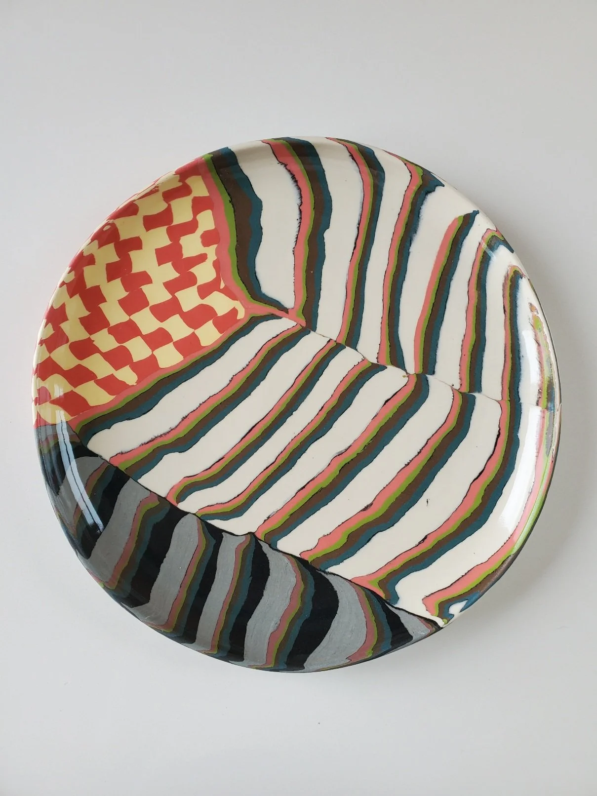 Colorful ceramic plate with abstract striped and checkered patterns