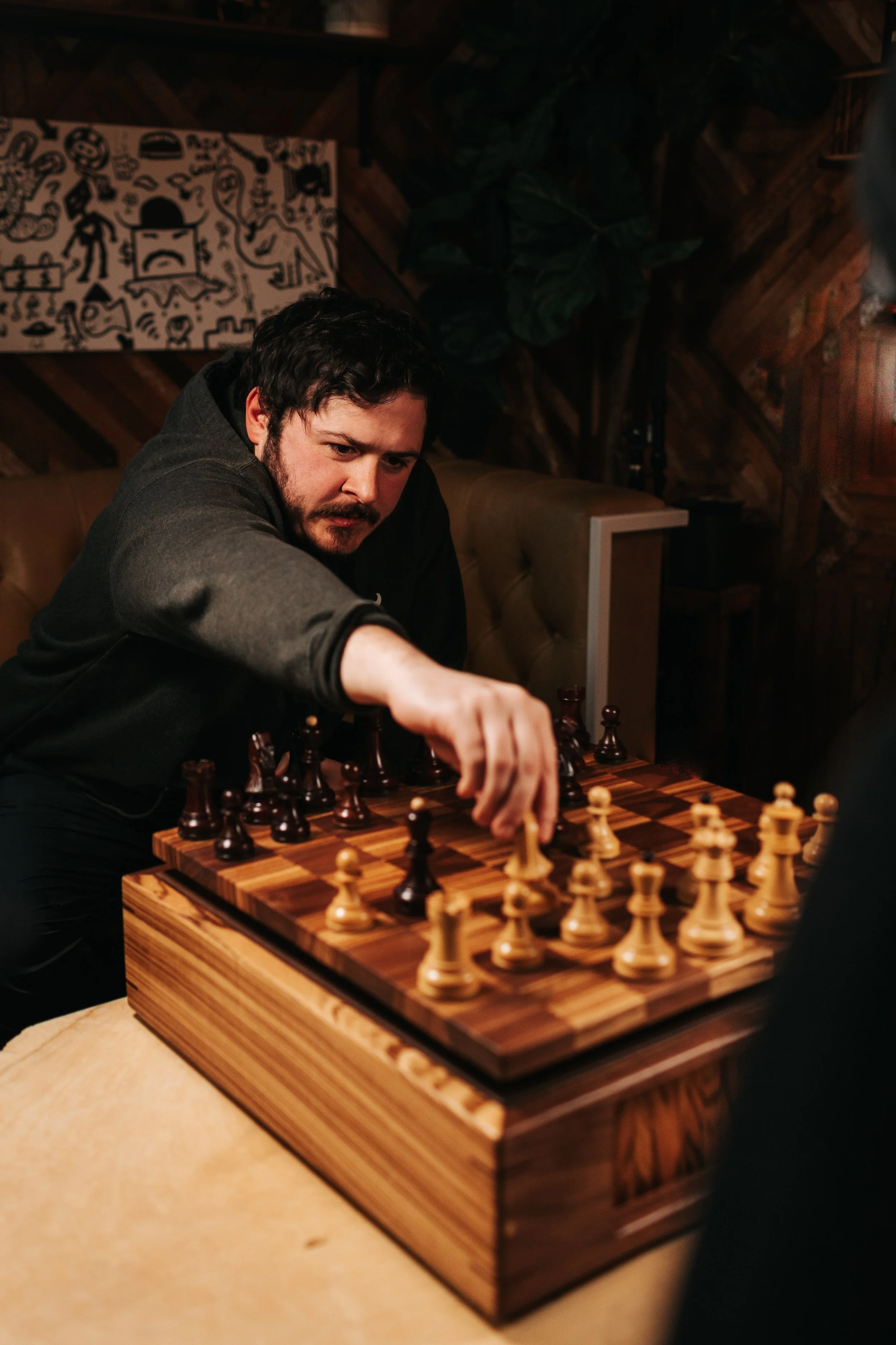 man playing chess on a handmade wooden chessboard