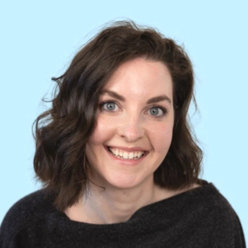 Julie Harris, a White smiling woman with blue eyes and dark brown hair wearing a black top. Headshot.