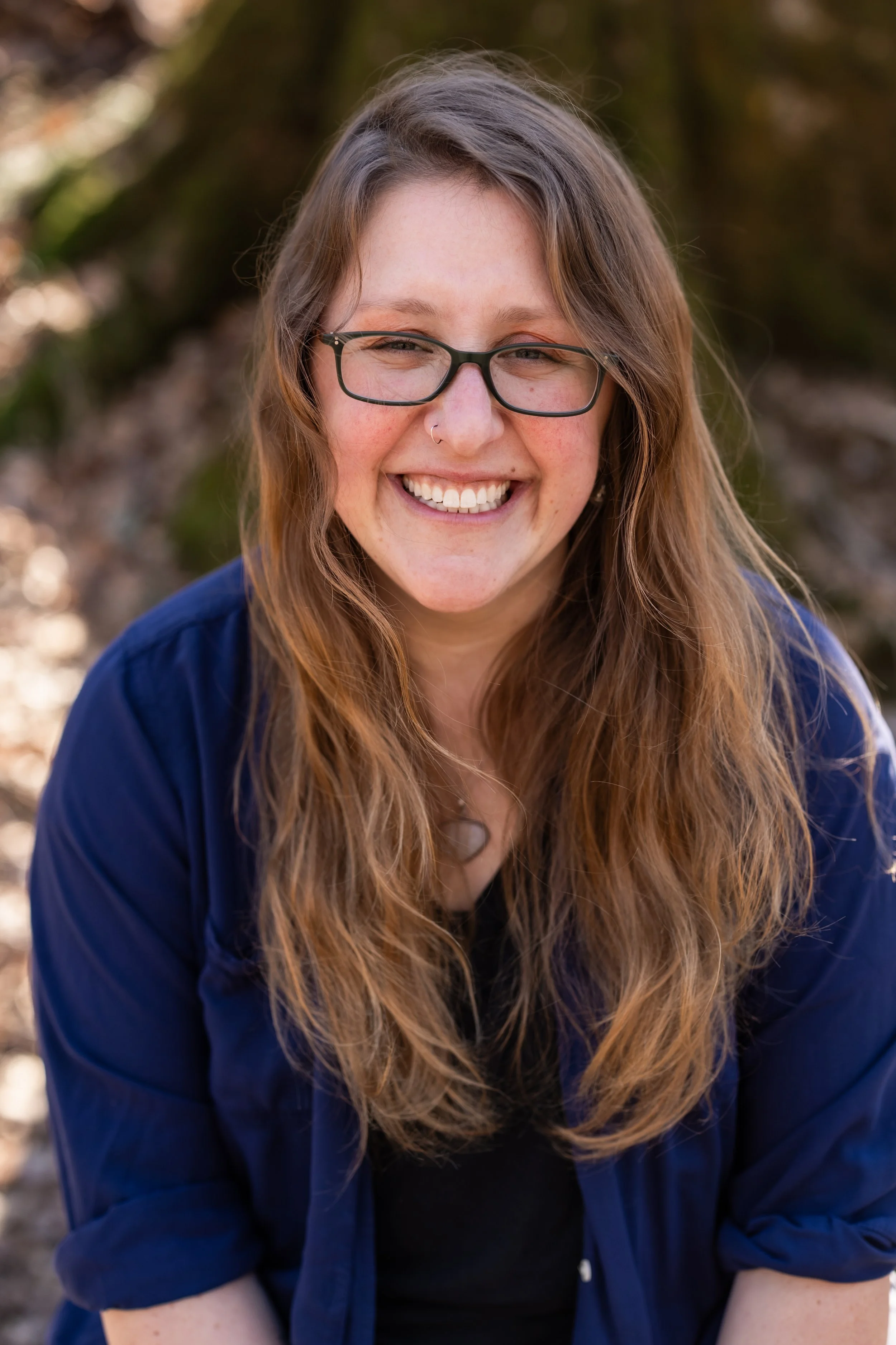 smiling dark blonde woman with glasses and a blue shirt