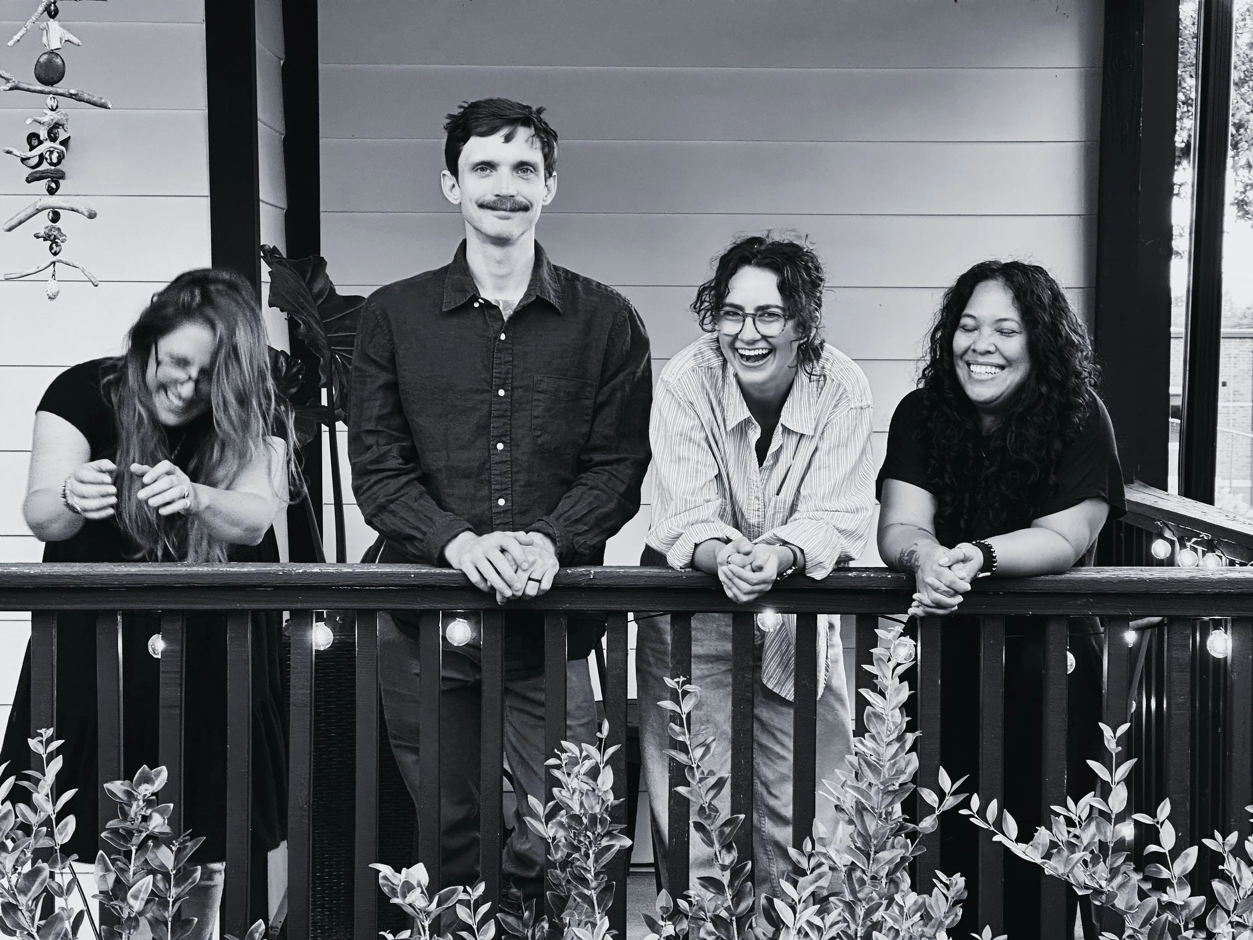 goofy black and white image of four out of five open door clinicians on the front porch of office house
