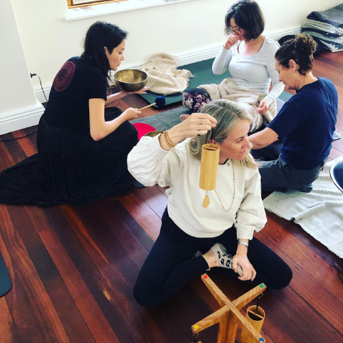 Four sound students seated together, one holding a chime and another a singing bowl.