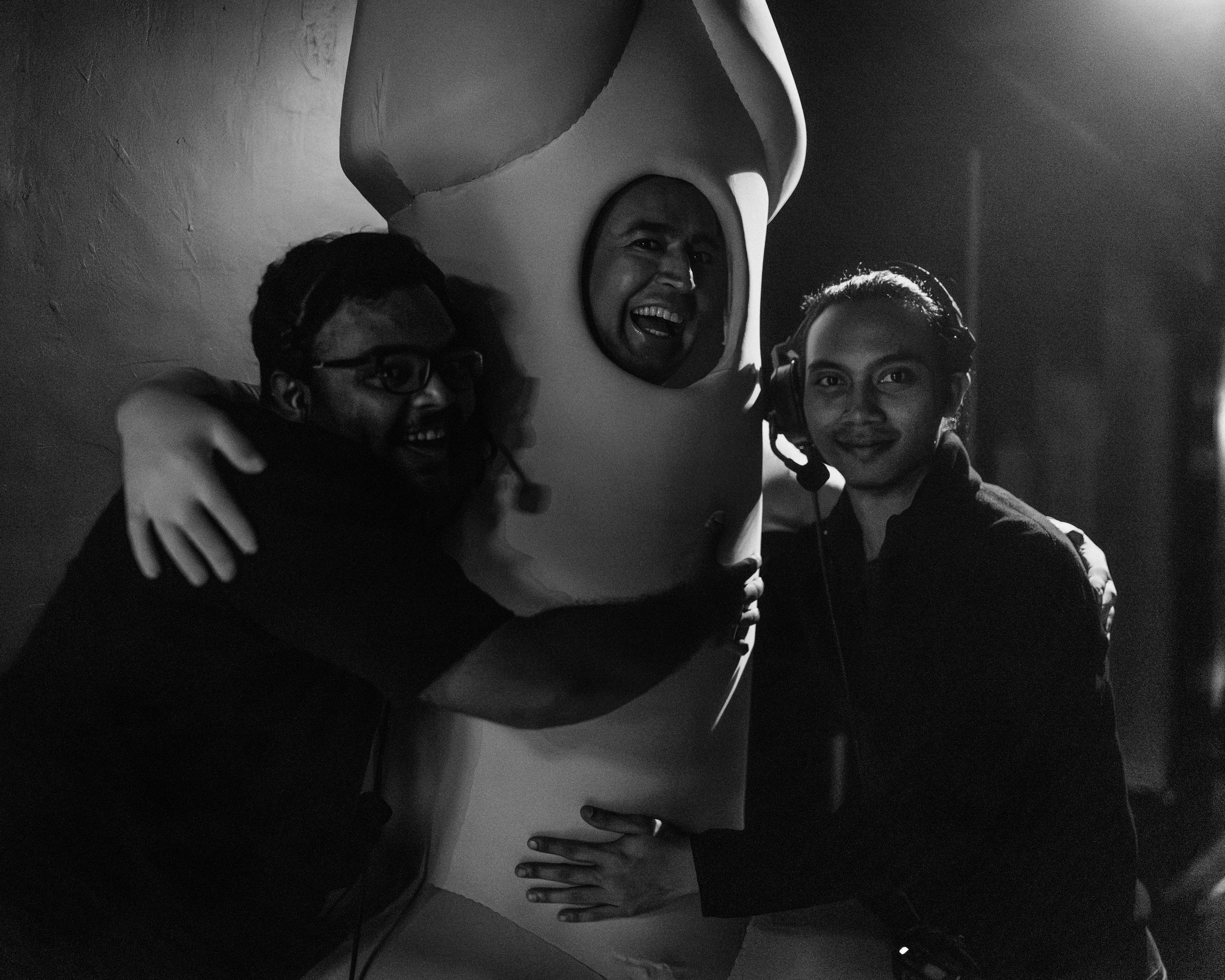 L to R: Head Mechanic Jayant Daniel Singh, Actor Ghafir Akbar (dressed as Penis), and Staging Technician Shafiq Jay share a hug backstage.