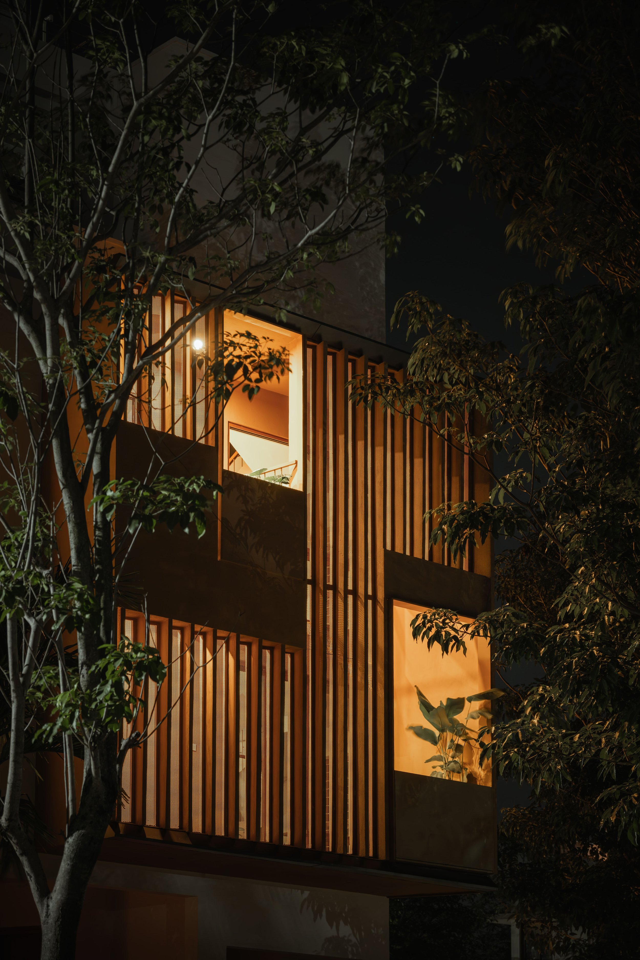 The façade at night, the screens lit from inside