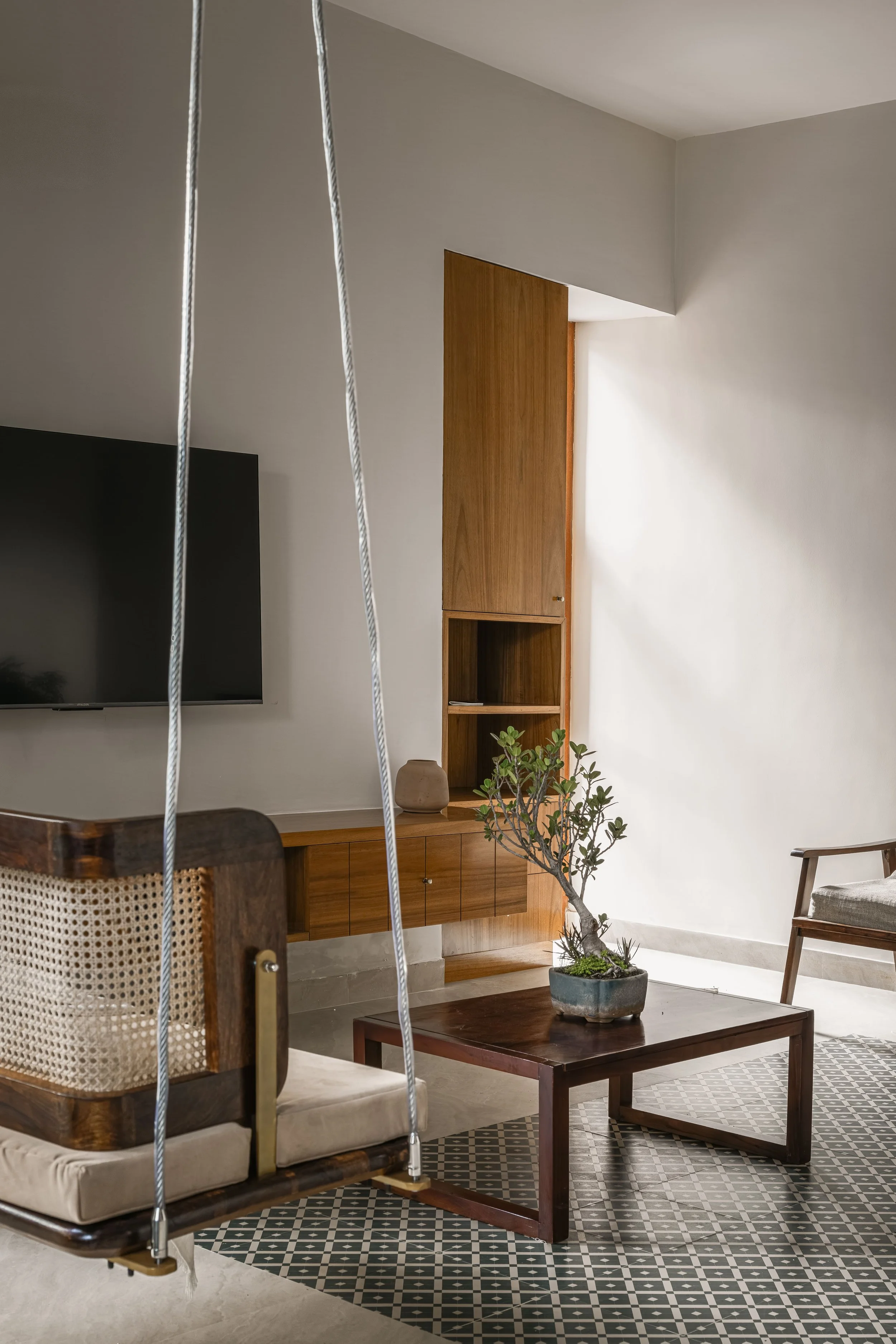 Living room with a swing, cane chairs and the television wall