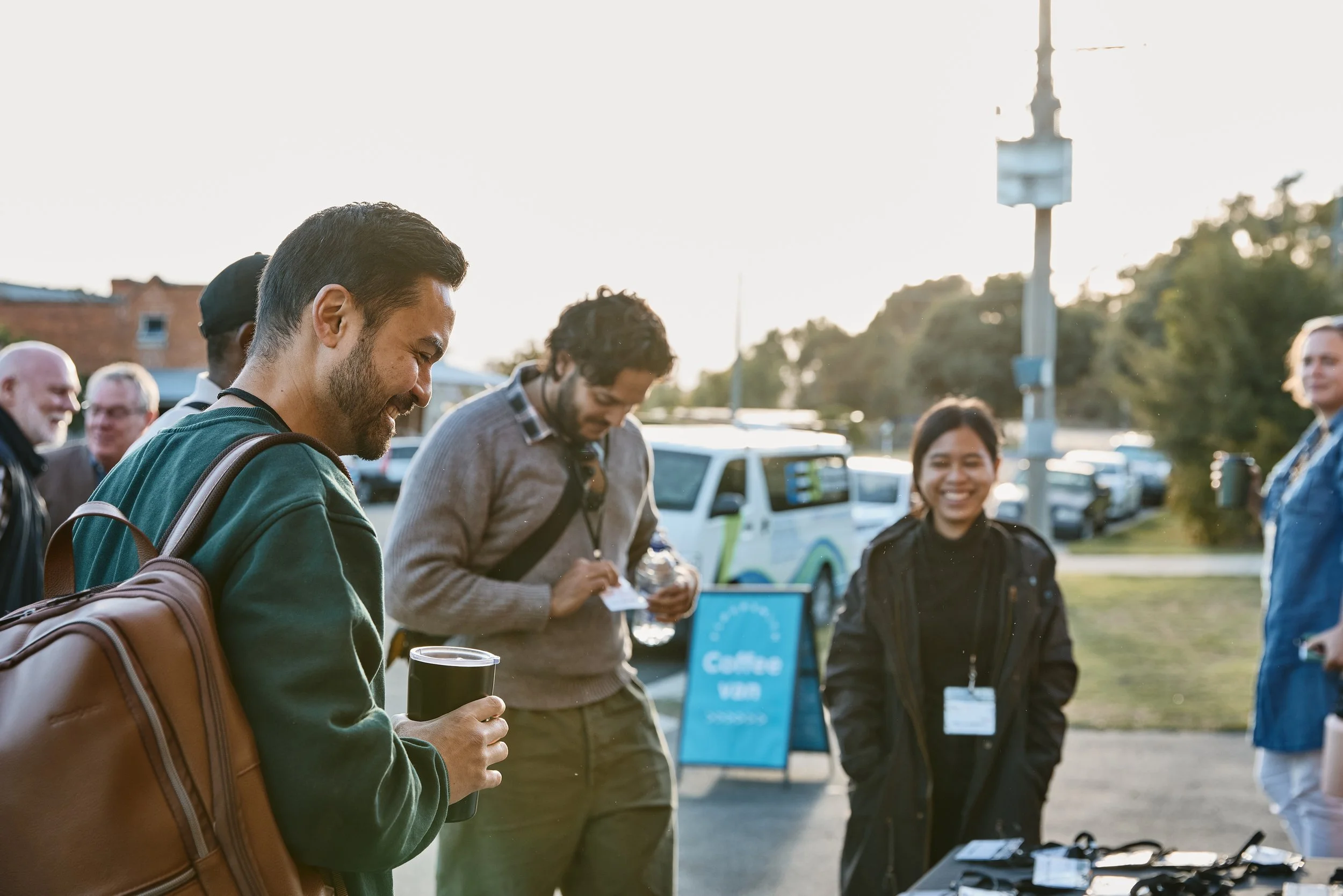 People stand around at an outdoor event, smiling.
