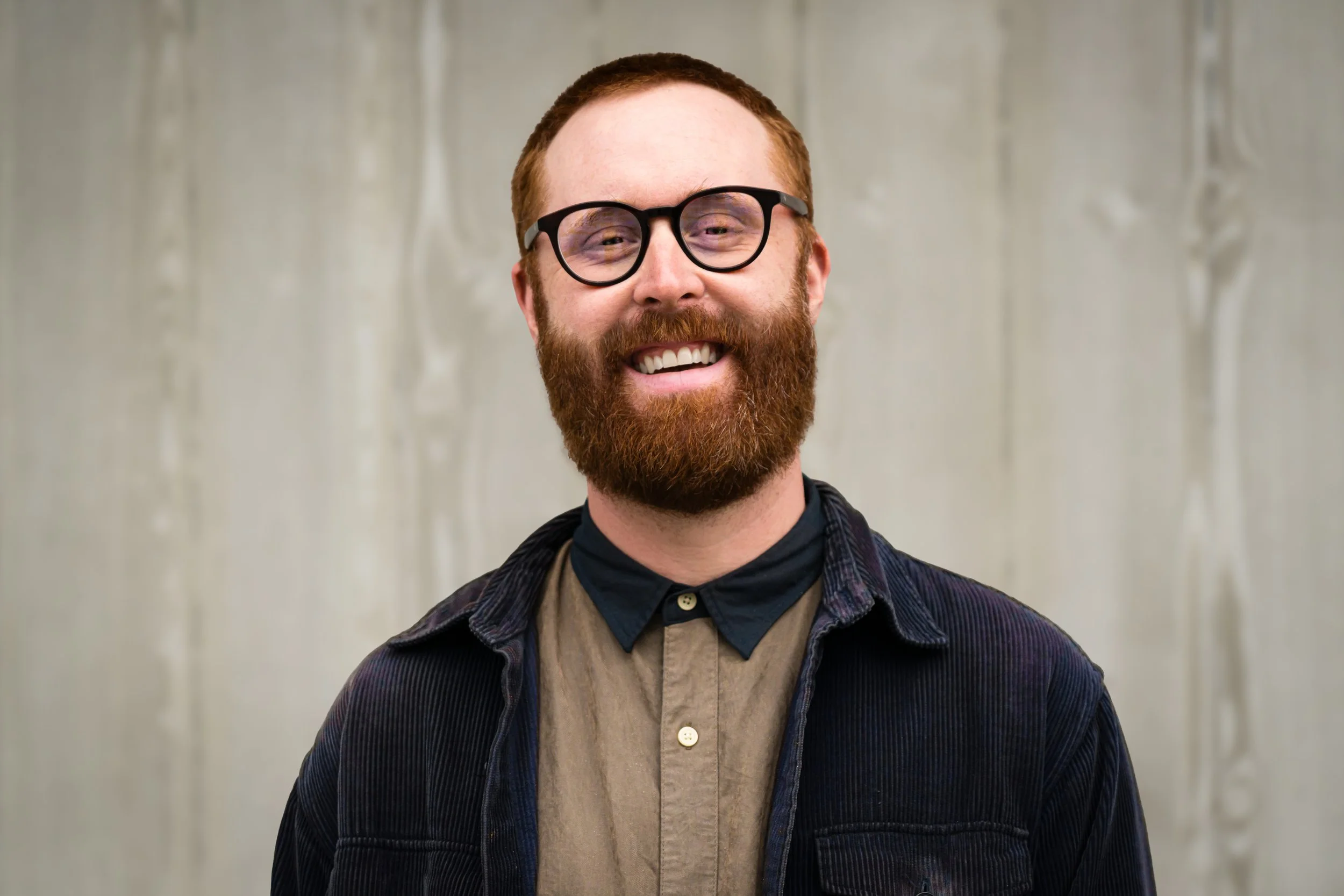 A man in glasses with a beard smiles at the camera