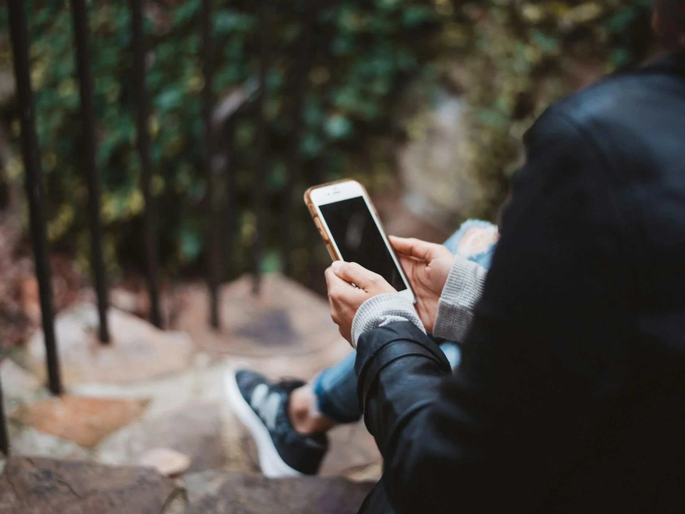 A person comfortably looking at their smartphone outside, representing the ease of scheduling a free consultation and accessing virtual telehealth therapy with Daybreak Therapy across TN, SC, and FL.
