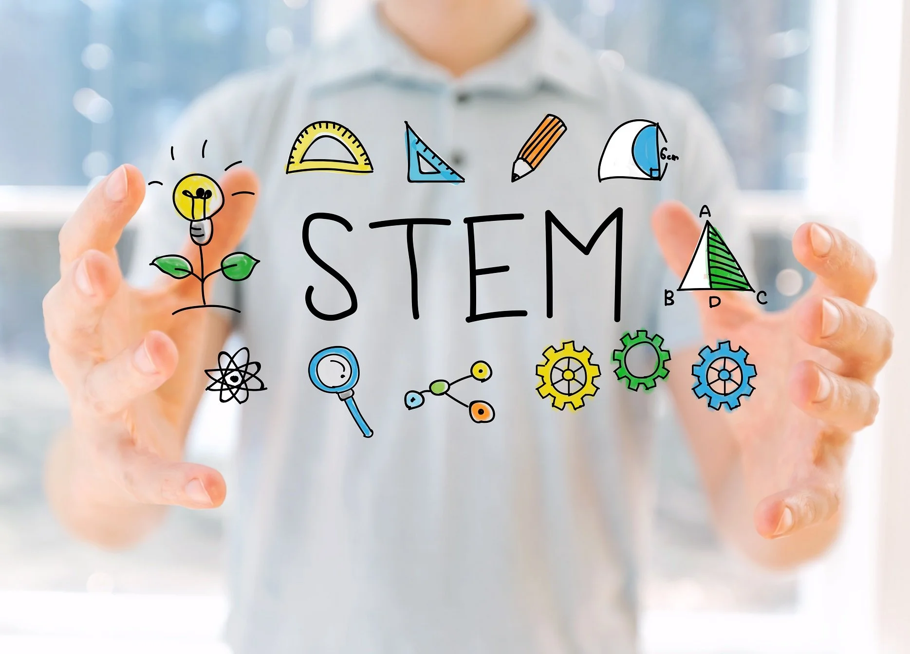 Person drawing a colorful 'STEM' diagram with icons of a lightbulb, ruler, triangle, magnifying glass, gears, atom, and other scientific symbols.