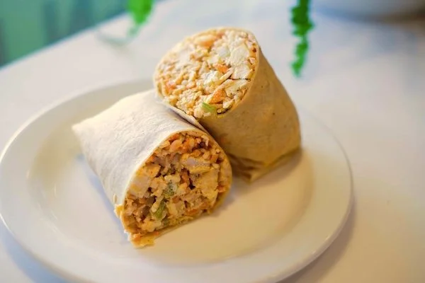 Two chicken burritos cut in half on a white plate