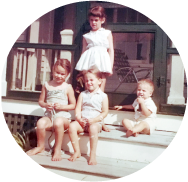Four children sitting and standing on a porch.