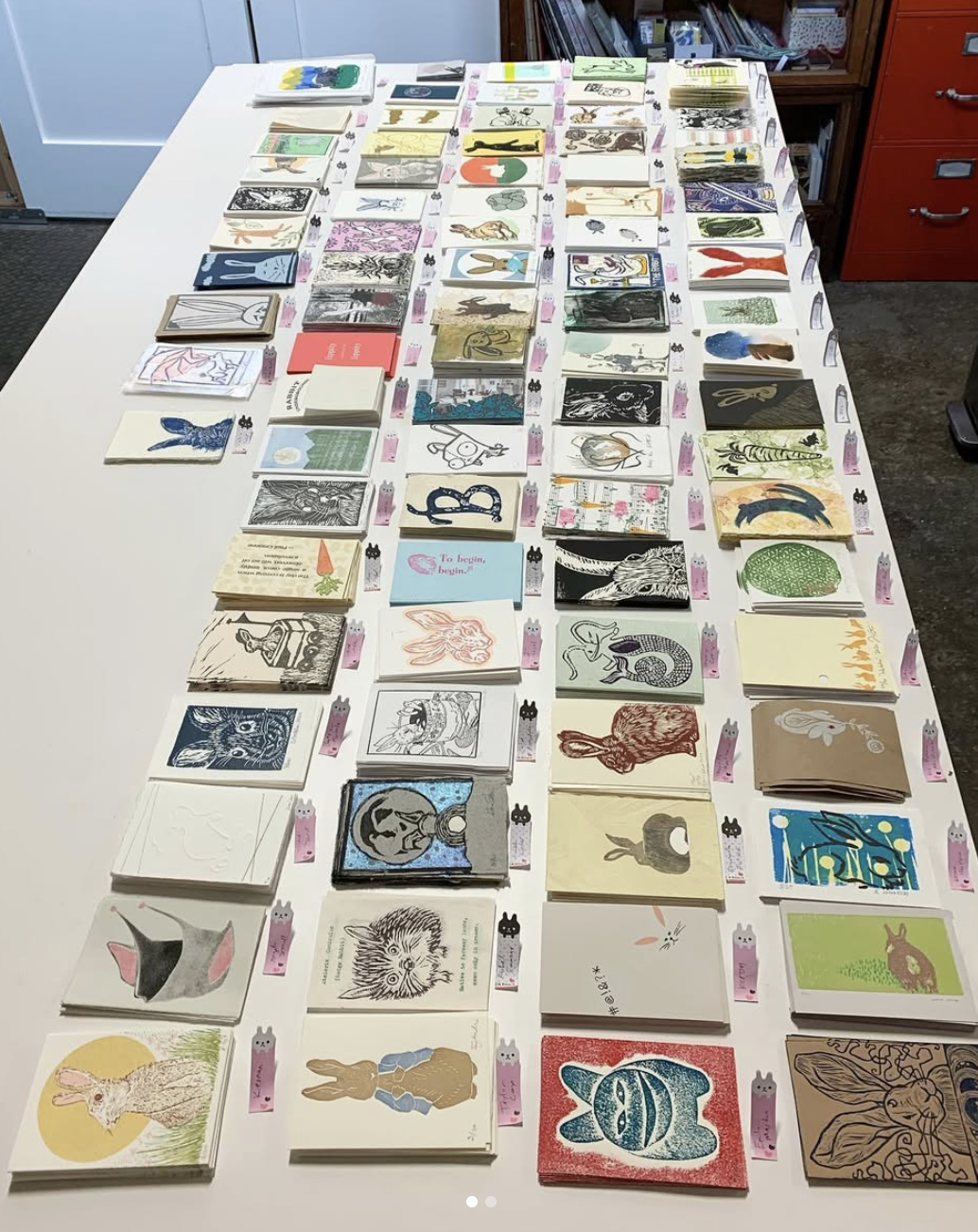 Prints from 2020 print exchange organized on table to be collated
