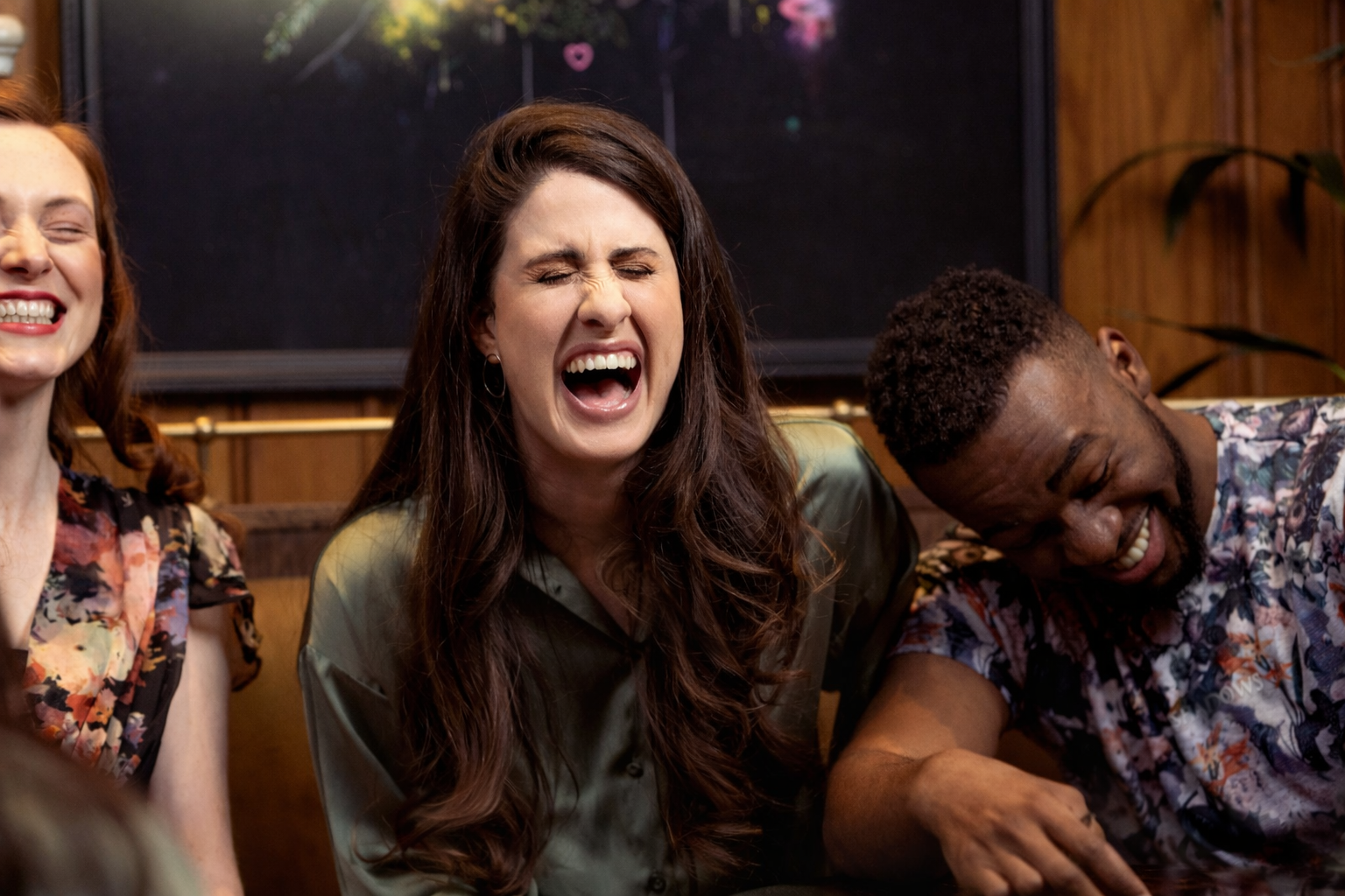 Three people laughing openly together, capturing a moment of genuine connection and shared joy.