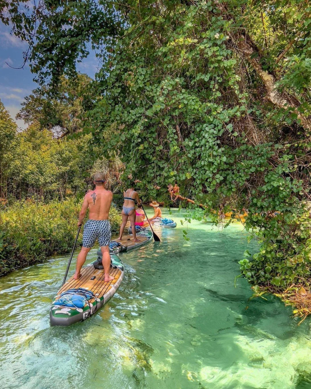 A group of friends stand up paddle boarding on holiday