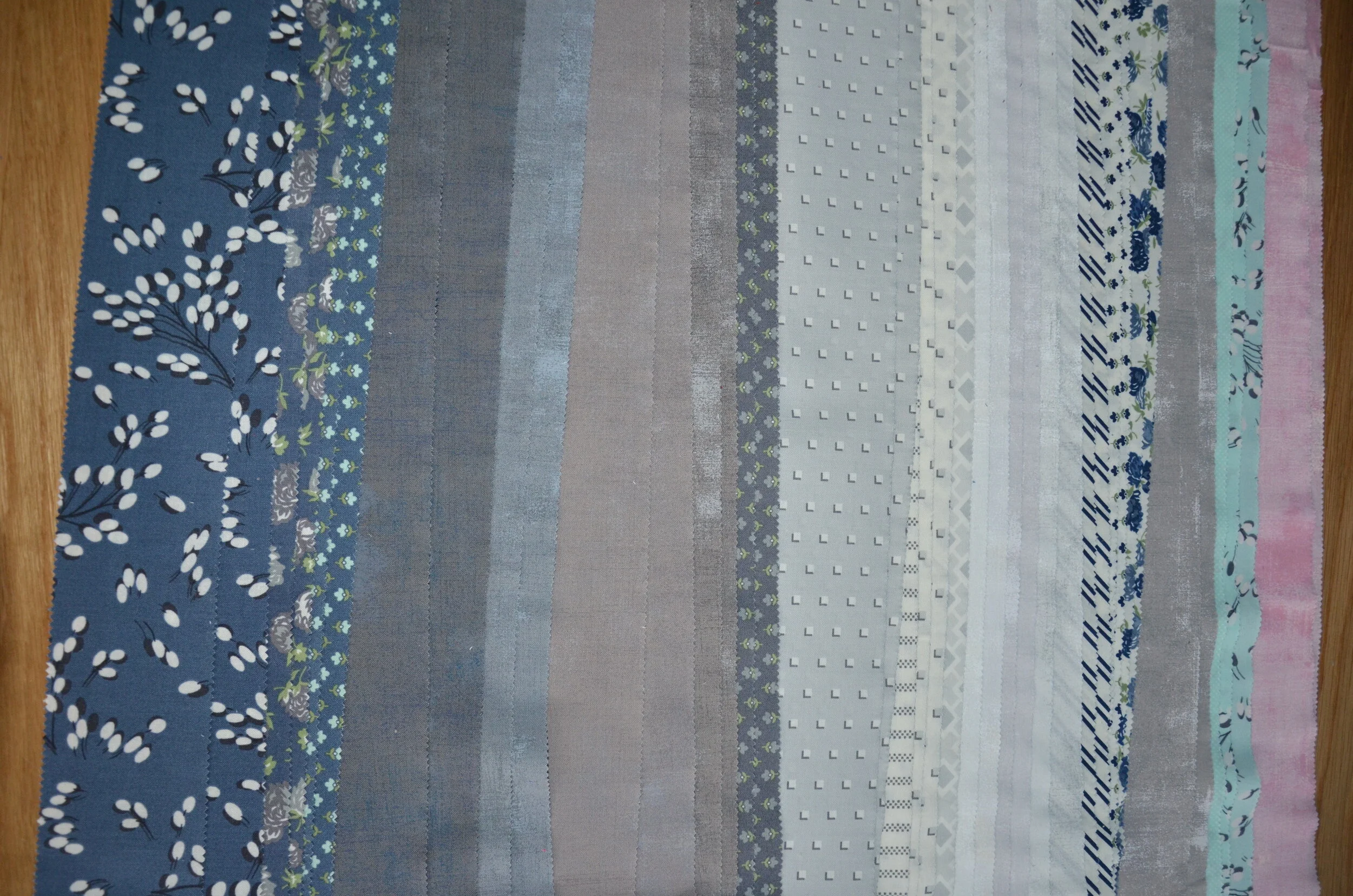 a collection of fabric in shades of blue, gray, white, green, and pink.