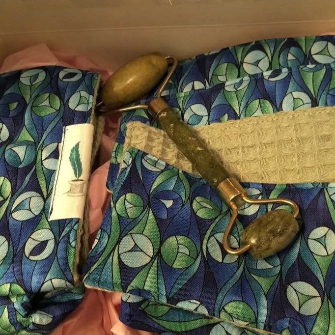 An open Healing Crystal Pamper Pack in Blue and Green Fabric- the pack includes two large Facial Cloths, Four Small Make Up Facial Cloths and a Hairband also with a Jade Facial Roller