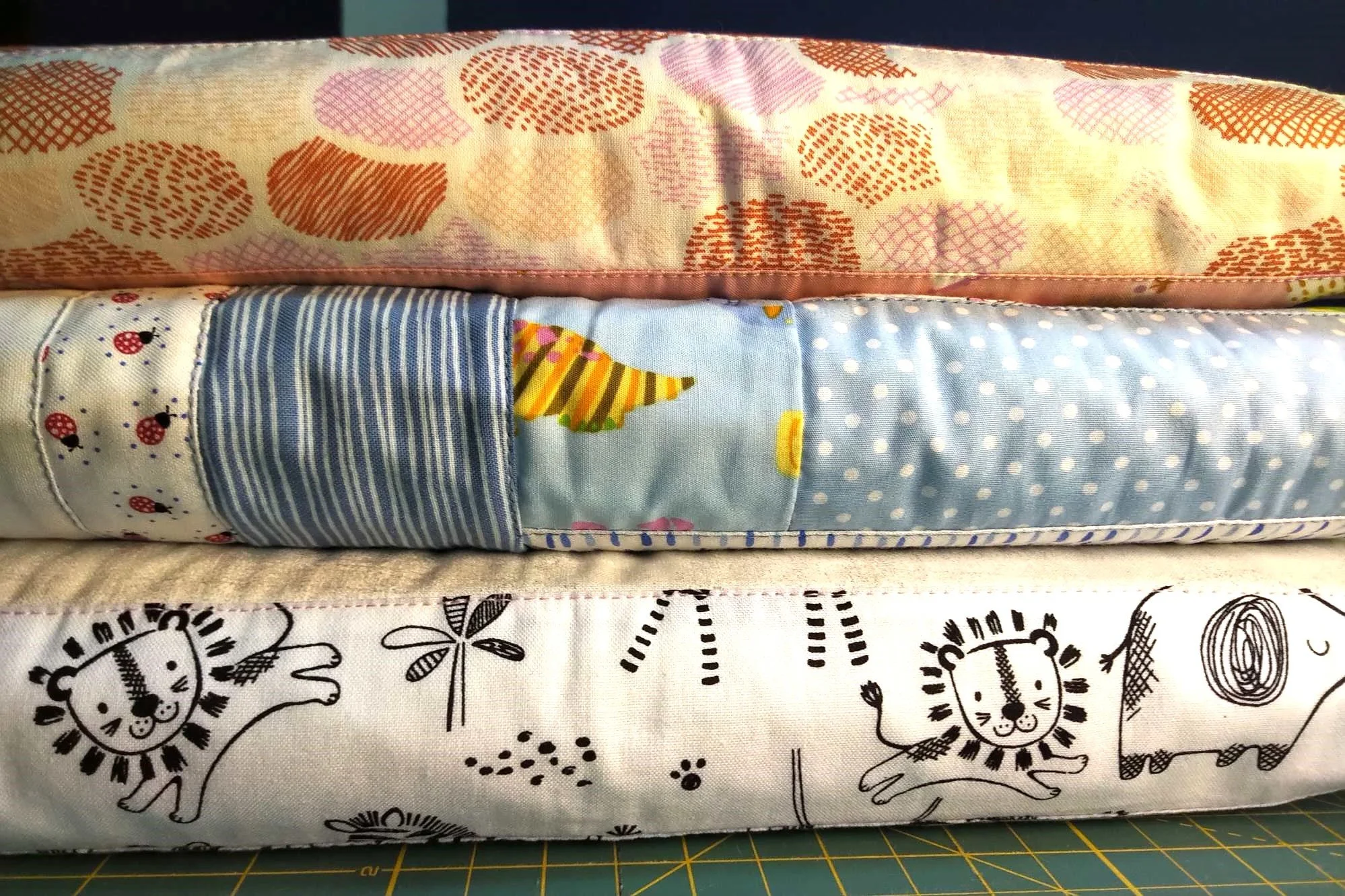 a bundle of baby quilts showing a blue, white and peach quilt .