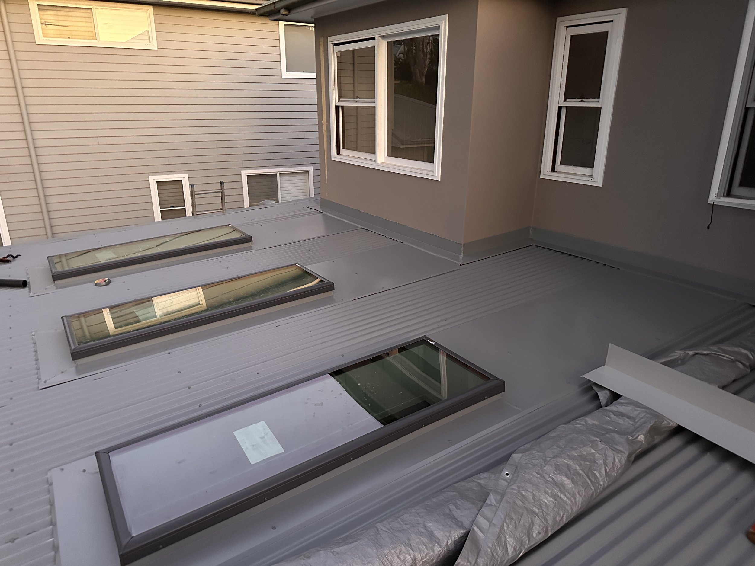 Roof with three skylights and a layer of insulation or protective material at the edge.