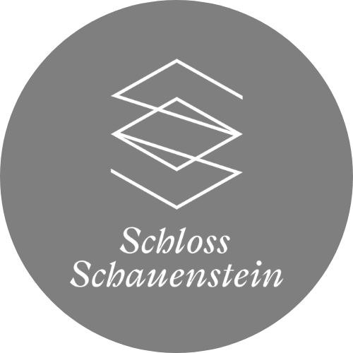 Ein schwarzes Bild mit einem weißen, geometrischen Schloss-Design und dem Text "Schloss Schauenstein" darunter.