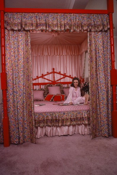 Helen Gurley Brown poses wearing a pink dress on her bed in her apartment on Central Park West, New York, New York, January 1979_susan wood_2.jpg
