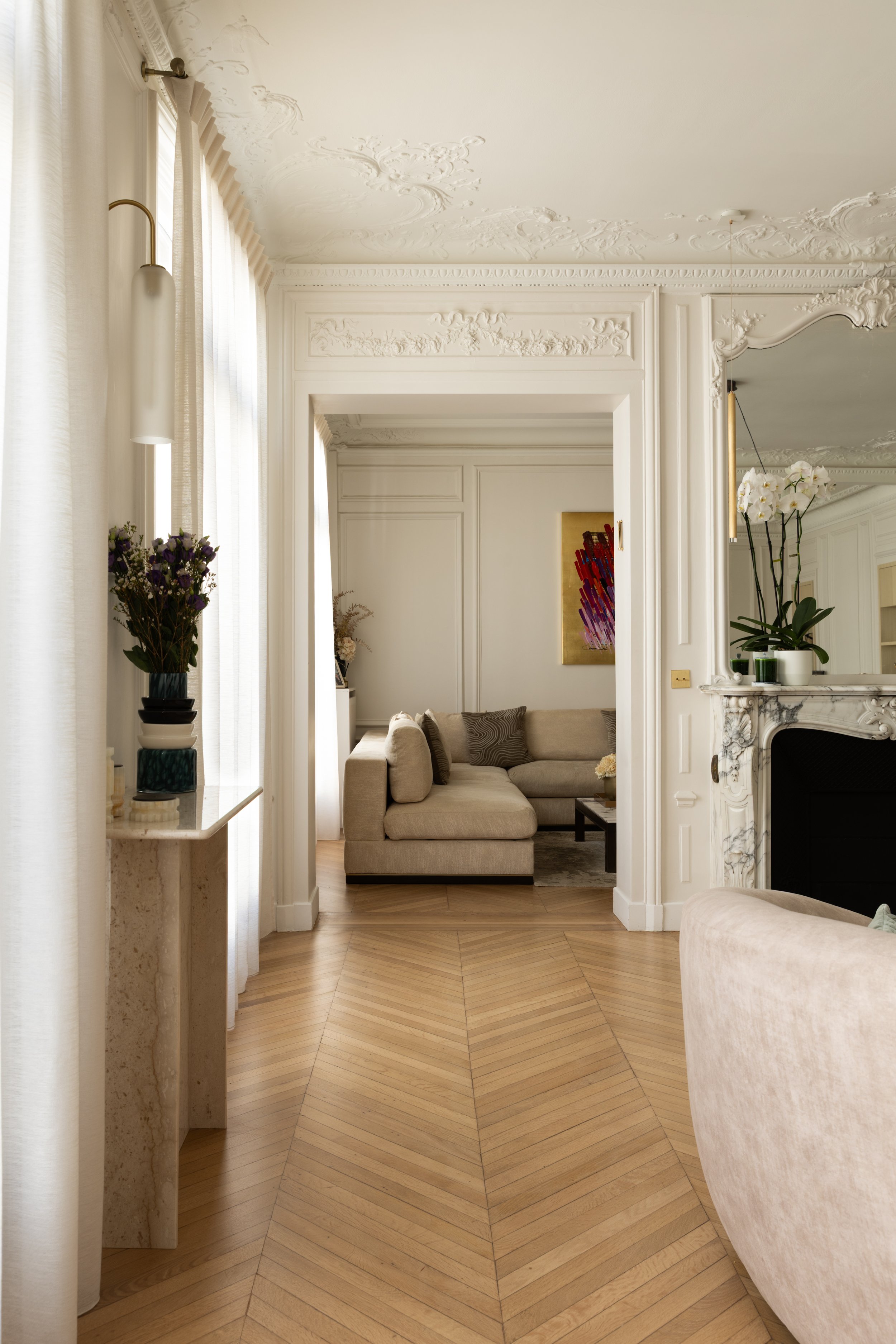 Perspective entre le salon de réception et le salon TV du projet Malesherbes à Paris, avec moulures haussmanniennes, cheminée en marbre et parquet en point de Hongrie — Intérieurs Chomet.