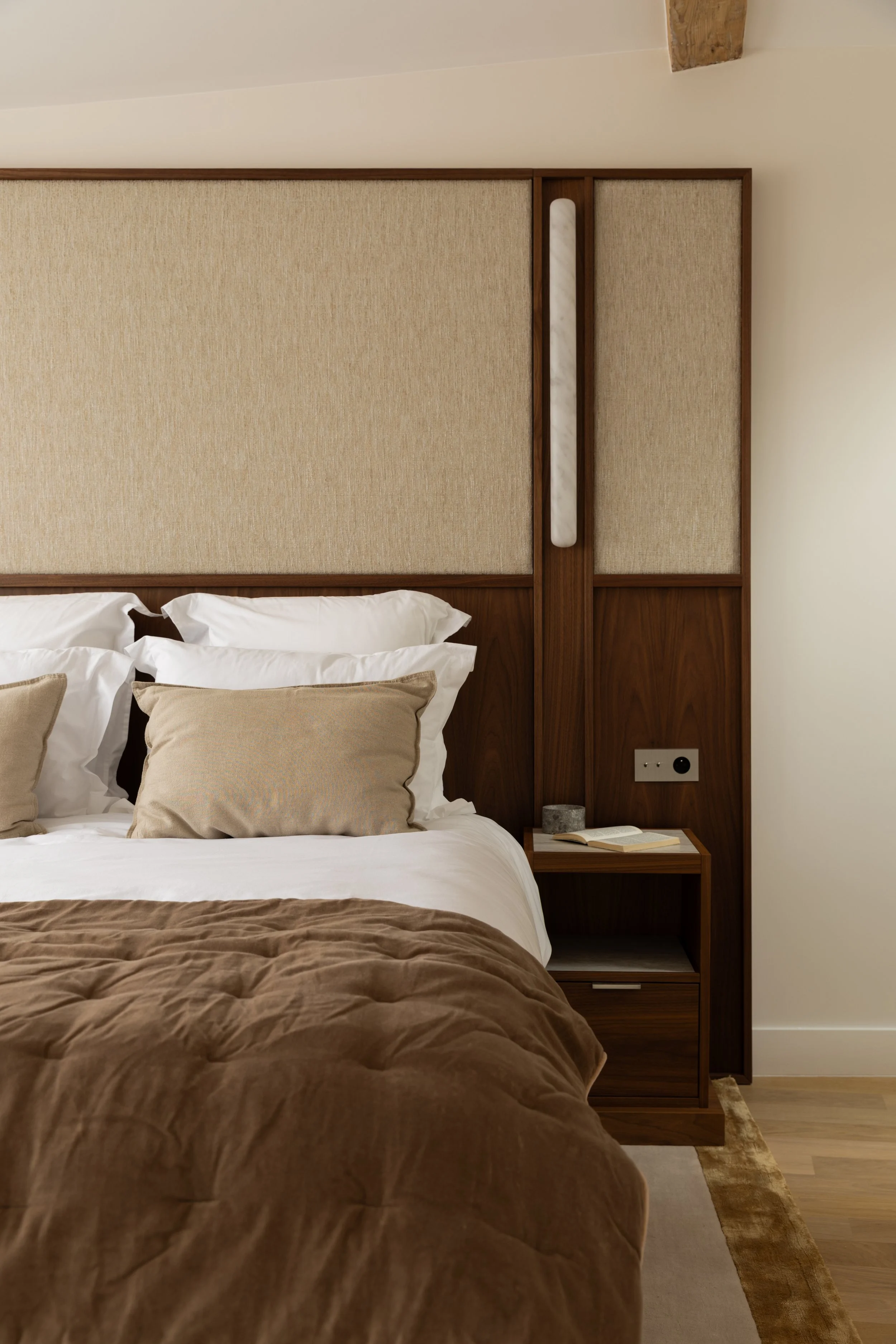 Tête de lit sur mesure en bois et tissu beige, éclairage intégré et mobilier raffiné dans une chambre parisienne – Intérieurs Chomet.