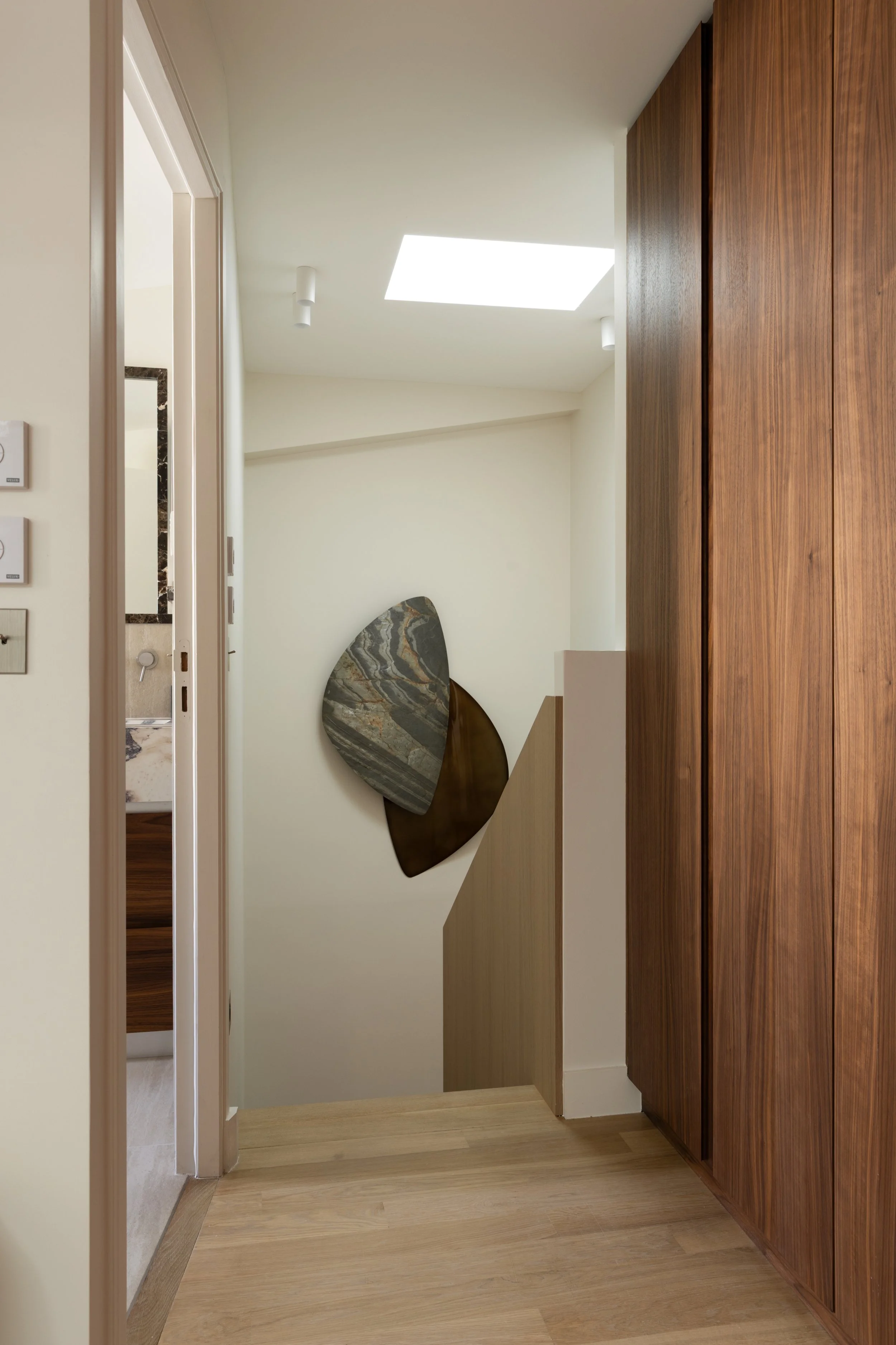 Aménagement d'un palier haut de gamme à Paris avec placards en bois sur mesure, parquet en chêne clair et décoration murale contemporaine – Intérieurs Chomet.