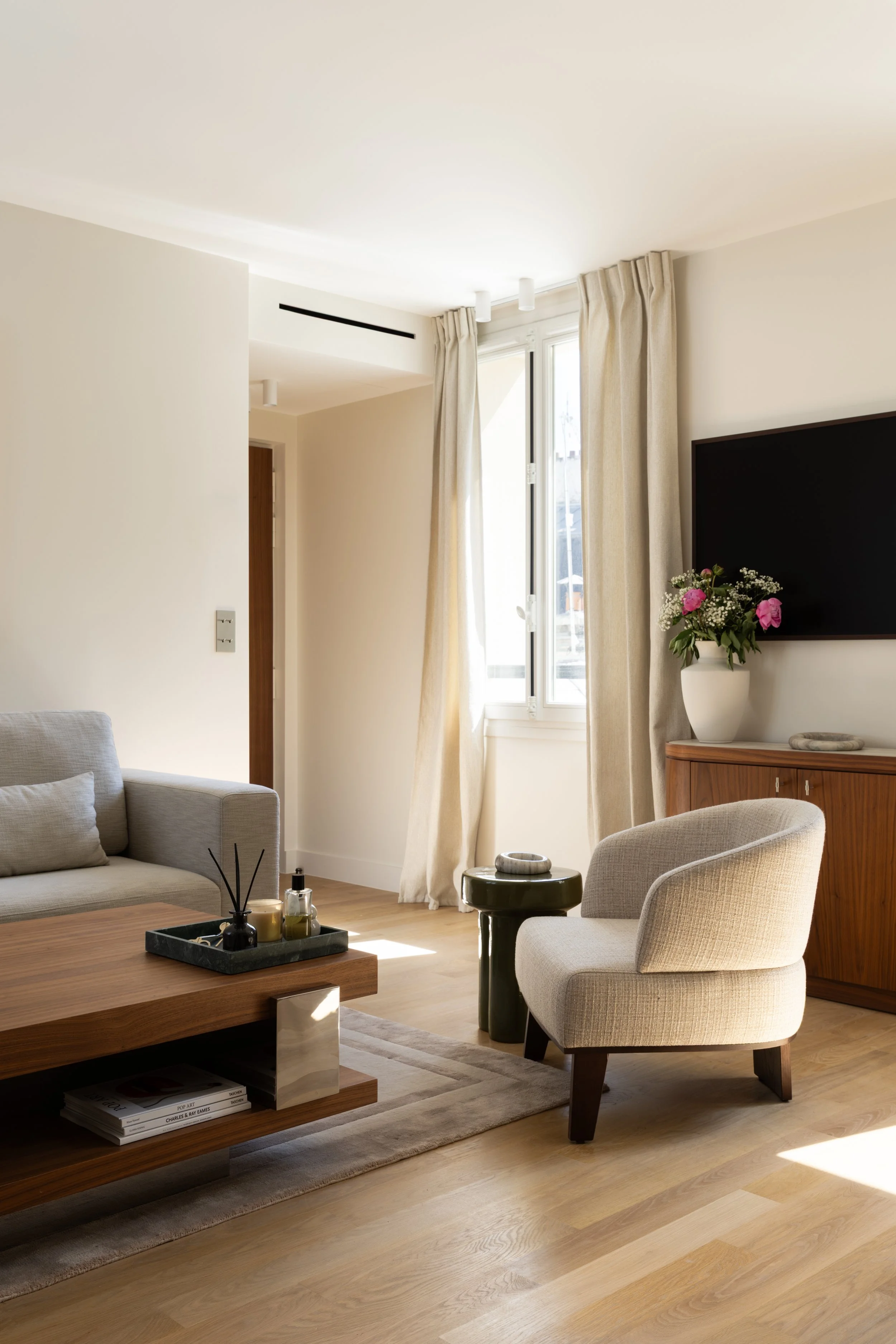 Petit salon contemporain à Paris avec fauteuil en tissu, table basse en bois, parquet clair et décoration chaleureuse – Intérieurs Chomet.