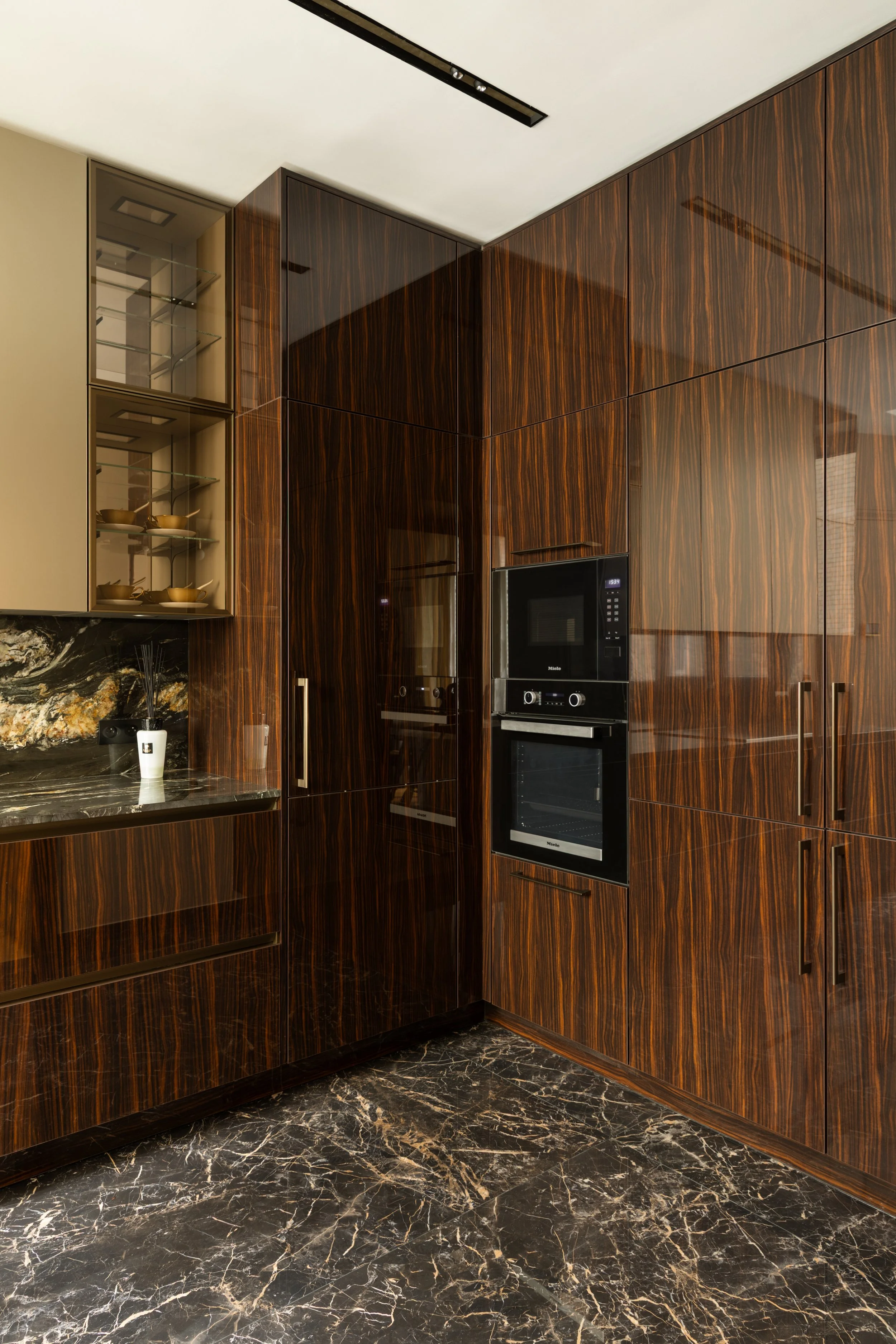 Cuisine décorée avec façades bois laqué brillant et crédence en pierre naturelle, design épuré et raffiné à Paris.