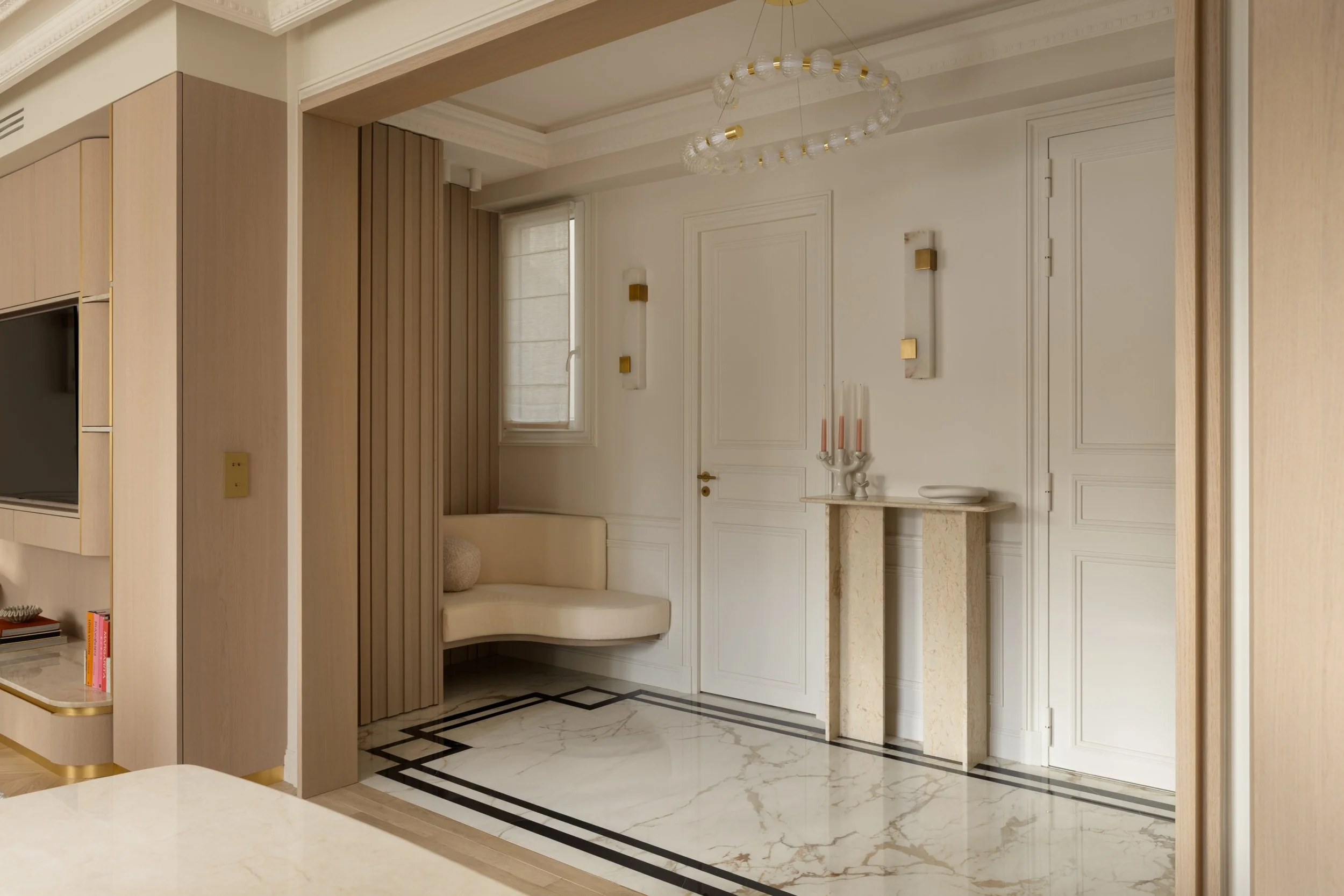 Entrée haussmannienne élégante avec moulures, banquette suspendue et console en pierre de David.