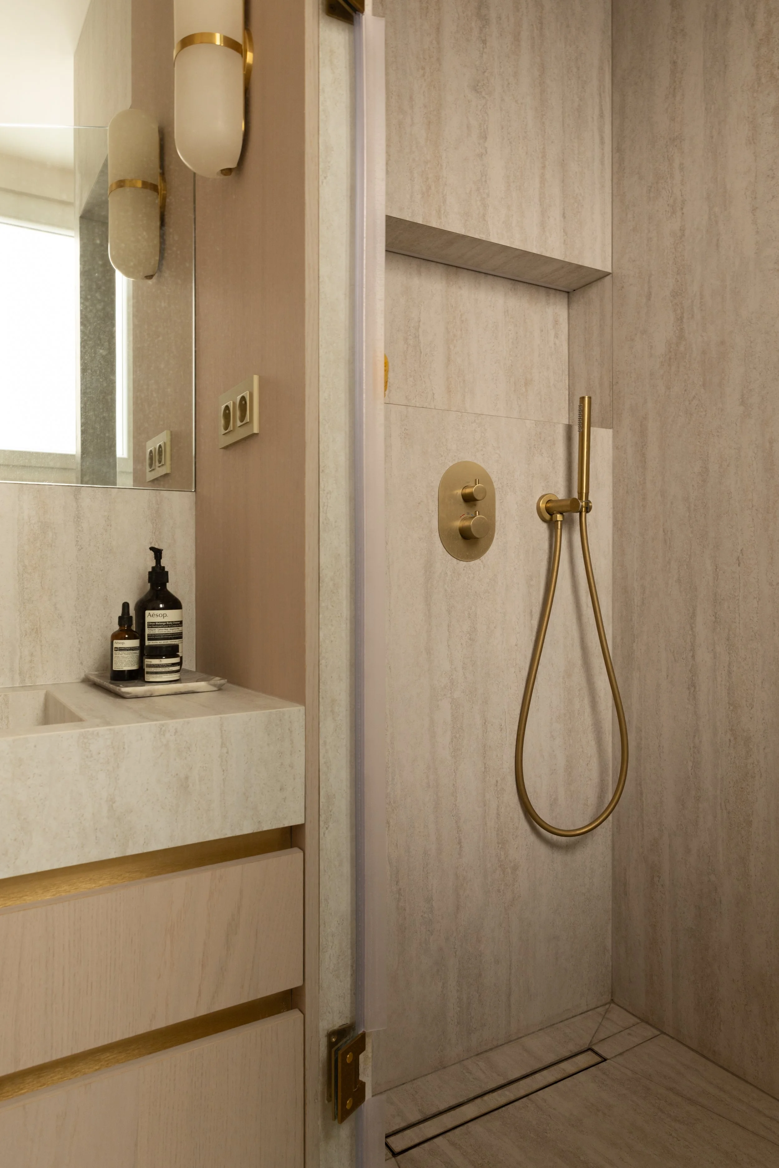 Douche à l’italienne minimaliste avec robinetterie dorée et finitions haut de gamme.