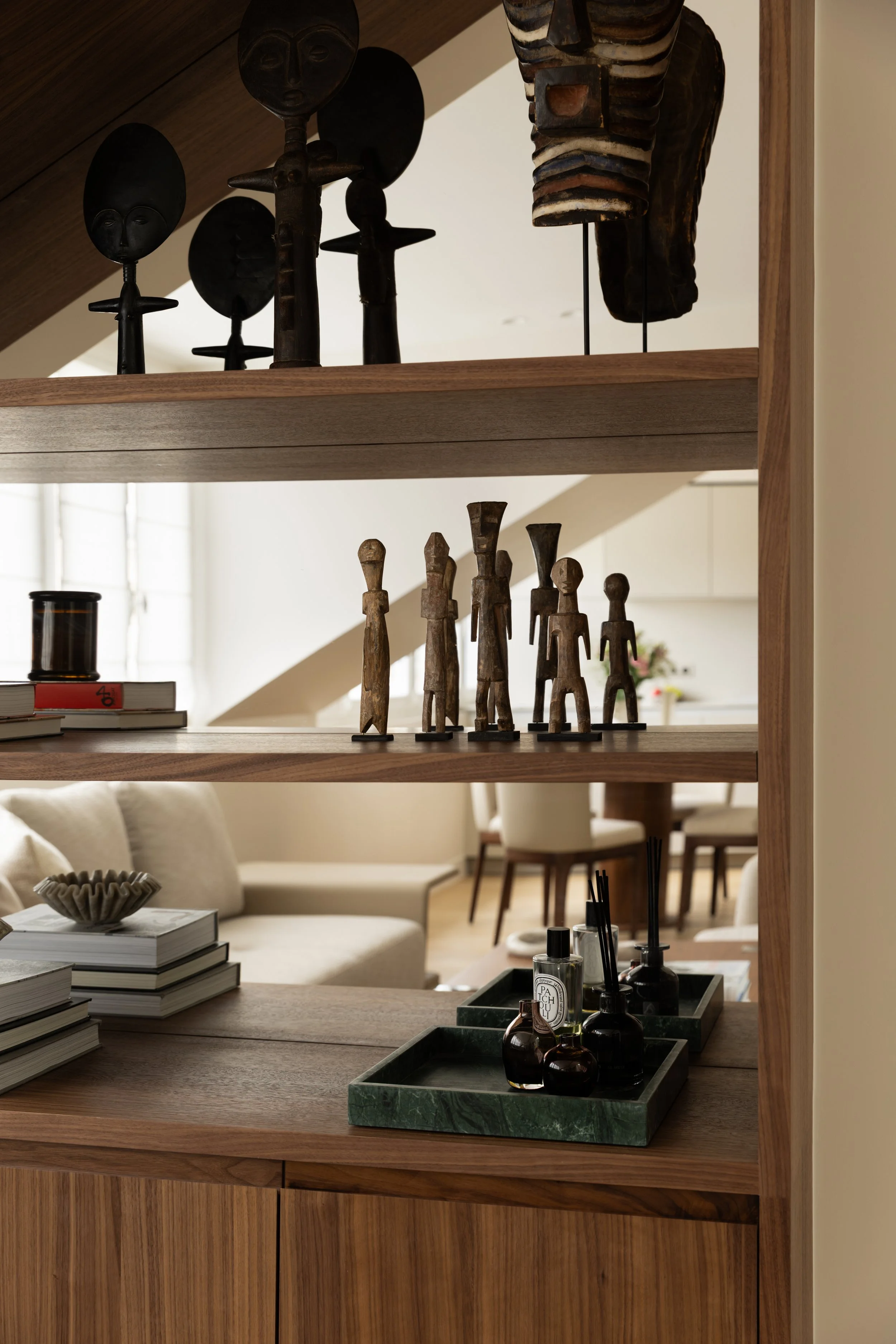 Bibliothèque sur mesure en bois naturel avec sculptures, objets d'art et décoration contemporaine dans un appartement parisien – Intérieurs Chomet.
