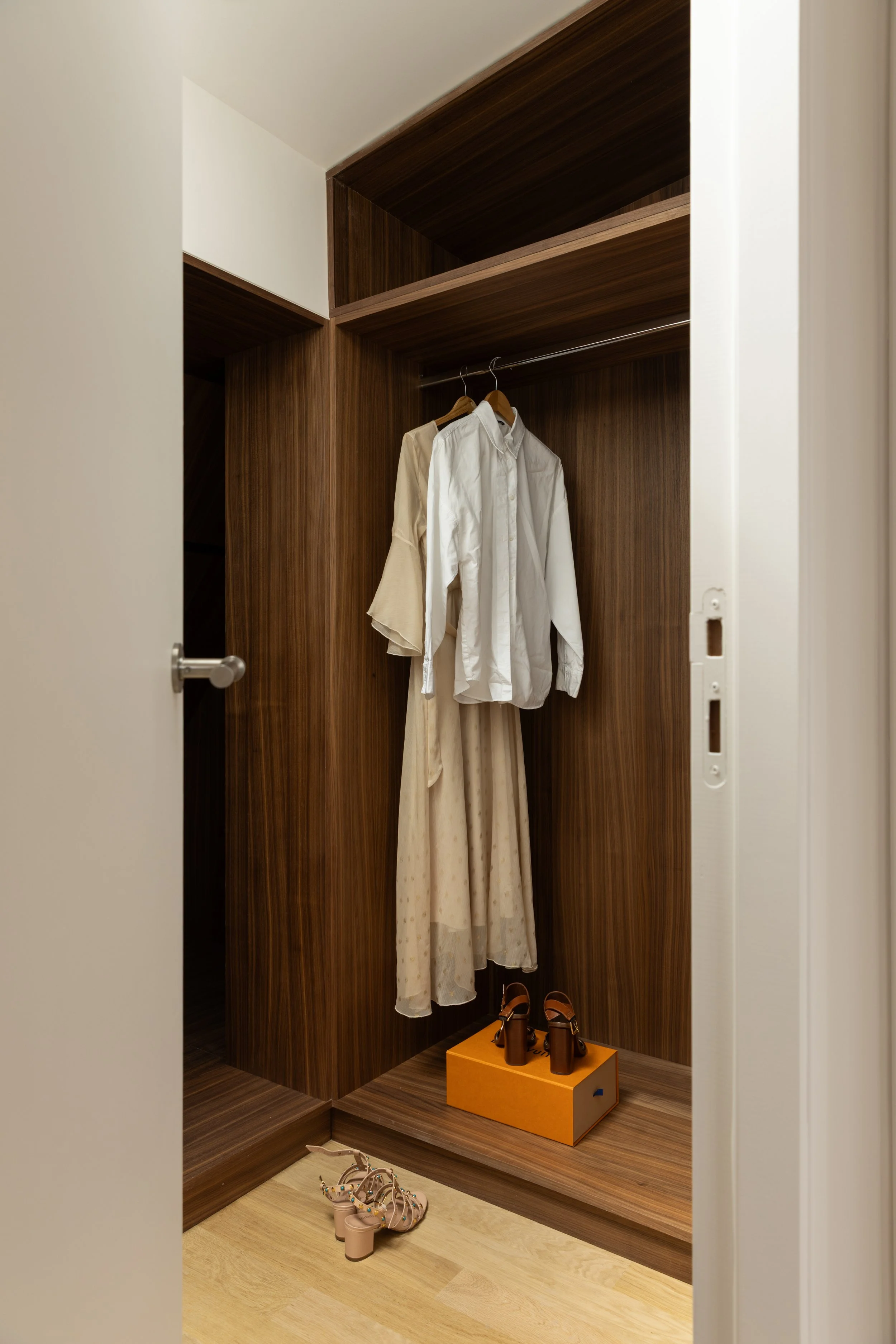 Dressing ouvert sur mesure à Paris avec rangements en bois foncé, penderies intégrées et finitions contemporaines – Intérieurs Chomet.