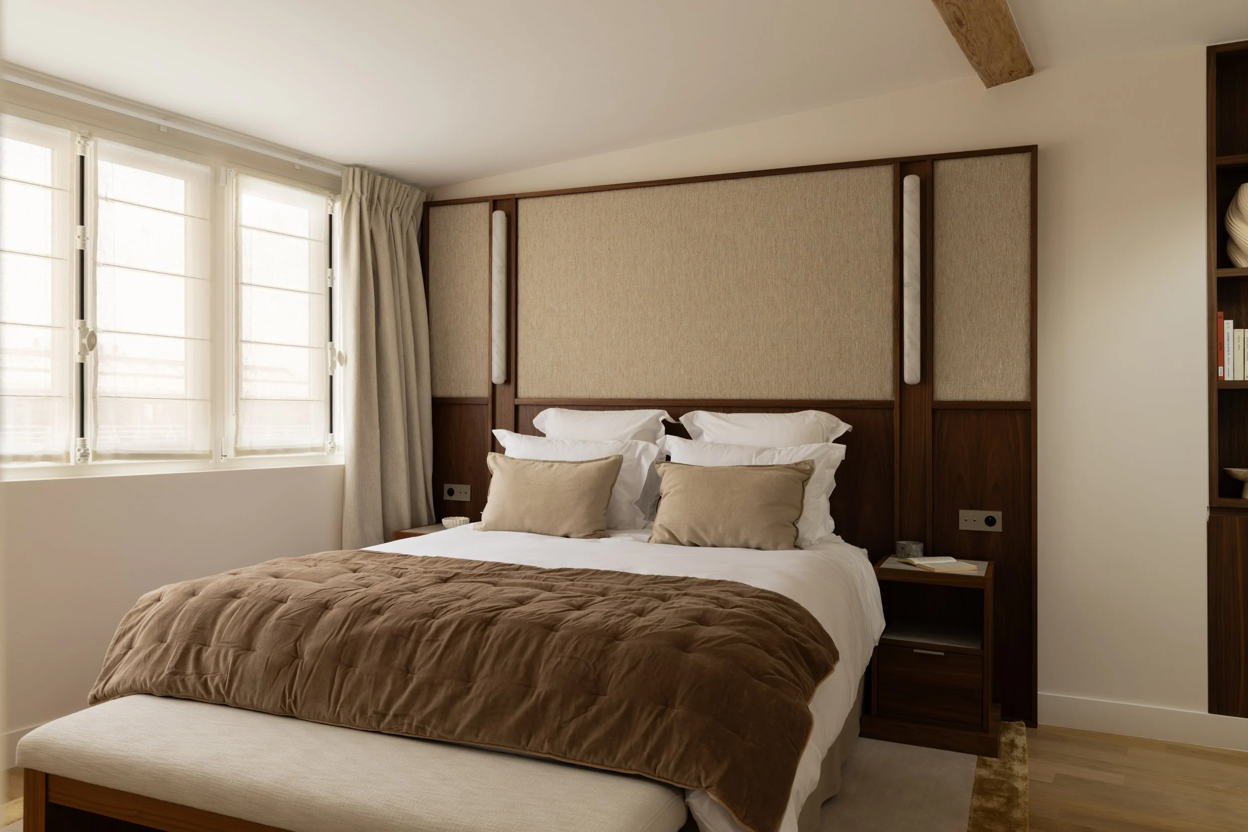 Chambre haut de gamme à Paris avec tête de lit sur mesure en bois et tissu, banquette de lit et décoration aux tons naturels – Intérieurs Chomet.