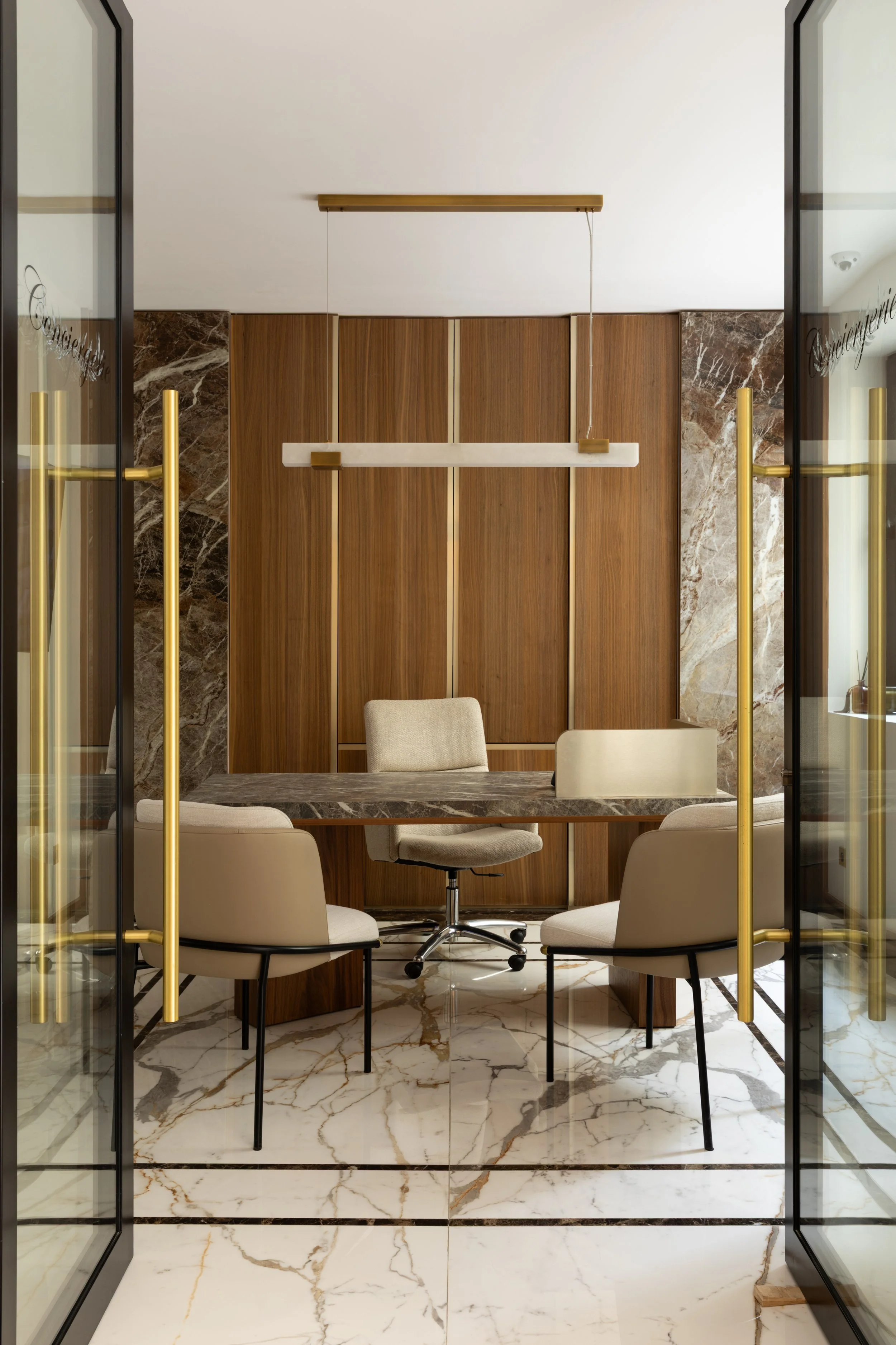 Aménagement d'un bureau privé haut de gamme à Paris avec marbre, boiseries sur mesure, fauteuils design et détails en laiton – Intérieurs Chomet.