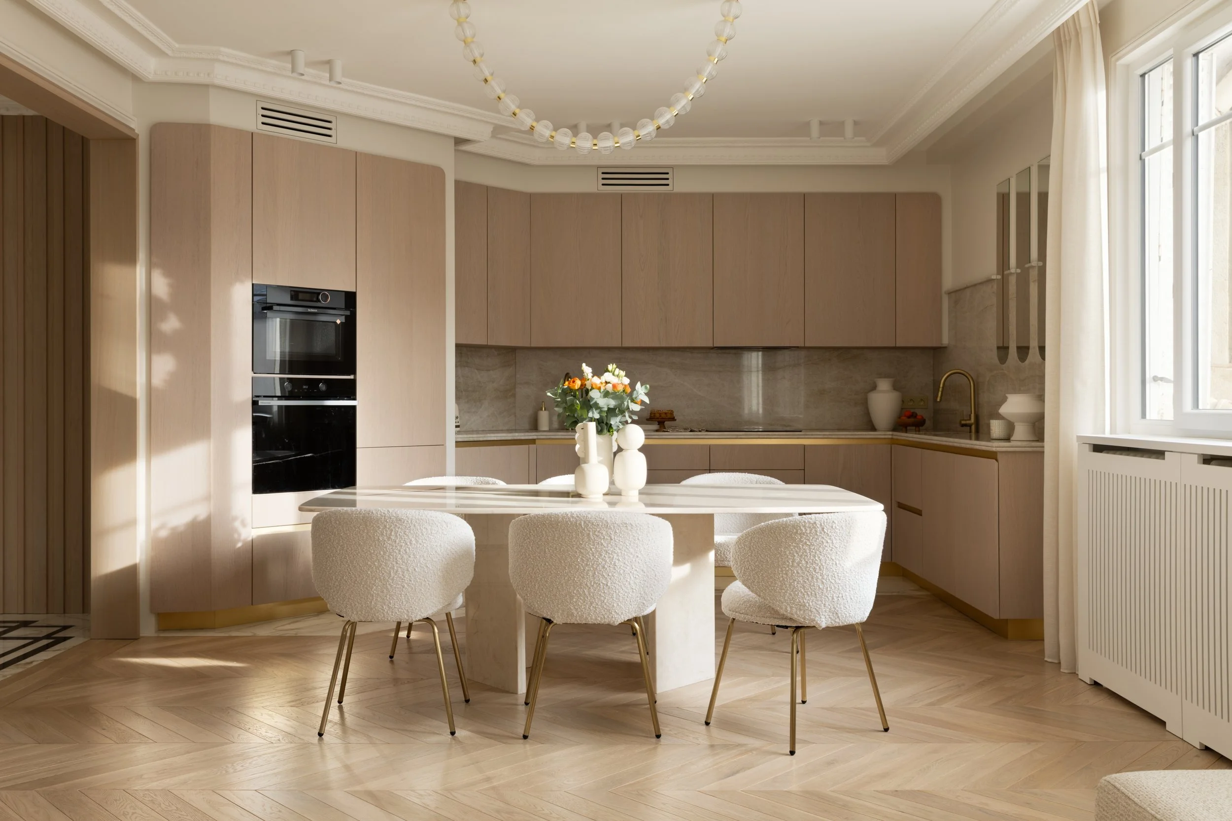 Cuisine salle à manger contemporaine avec table en marbre et chaises en bouclettes et pieds laiton et éclairage design.