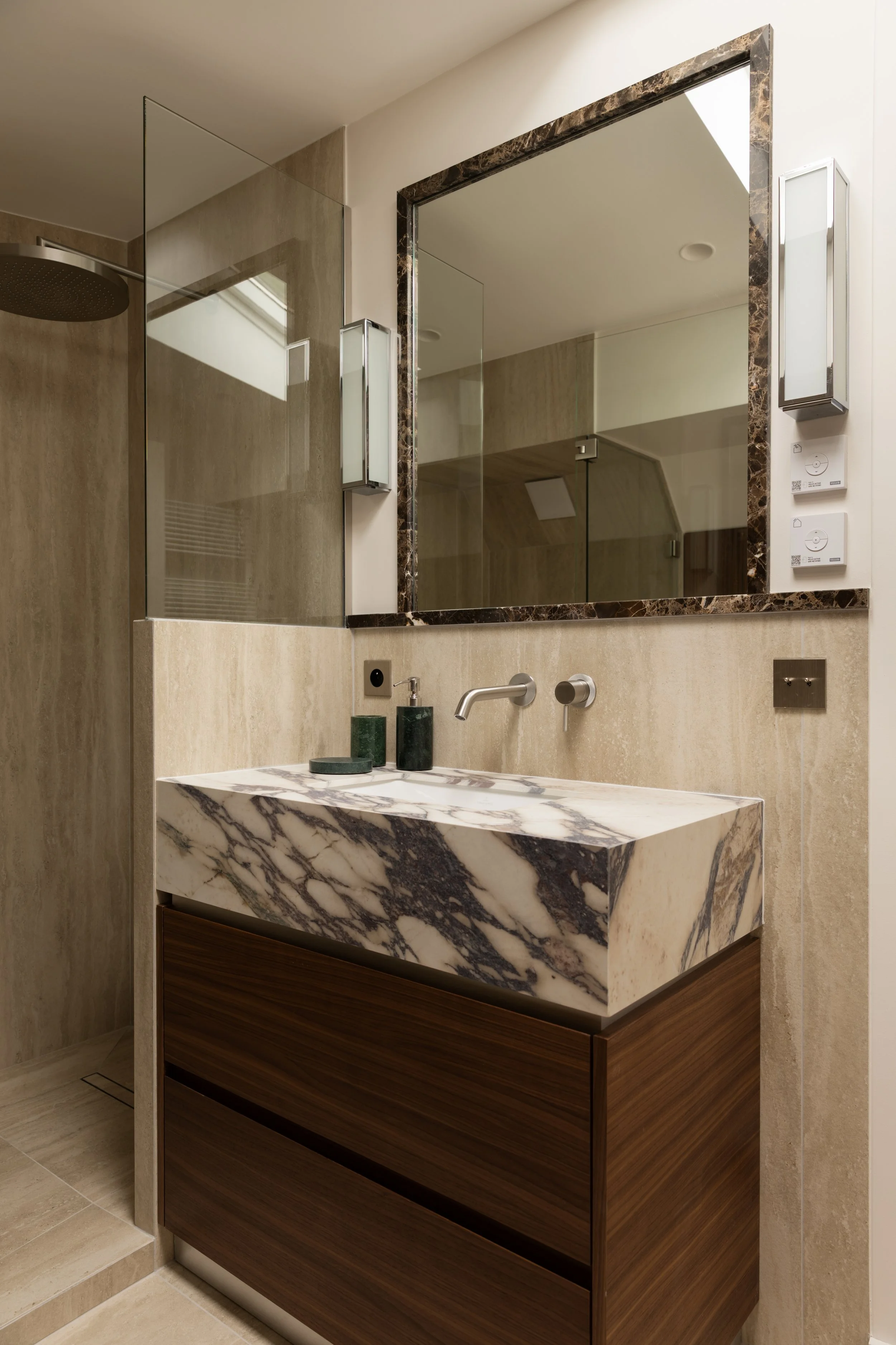 Salle de bains haut de gamme à Paris avec vasque en marbre veiné, meuble en bois sur mesure et douche vitrée – Intérieurs Chomet.