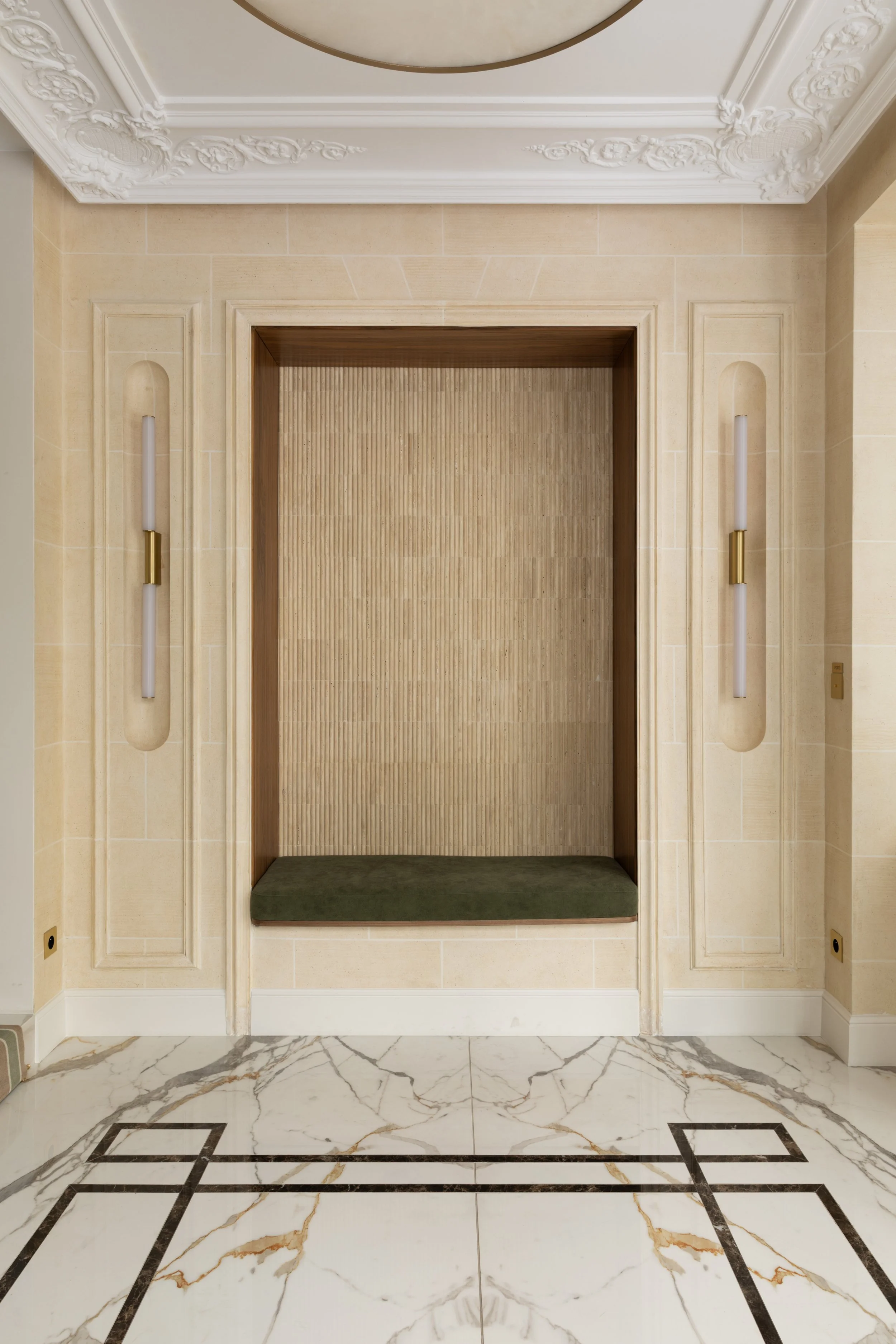 Niche architecturale en pierre naturelle avec banquette en velours vert, appliques en laiton et sol en marbre – Architecture d'intérieur à Paris.
