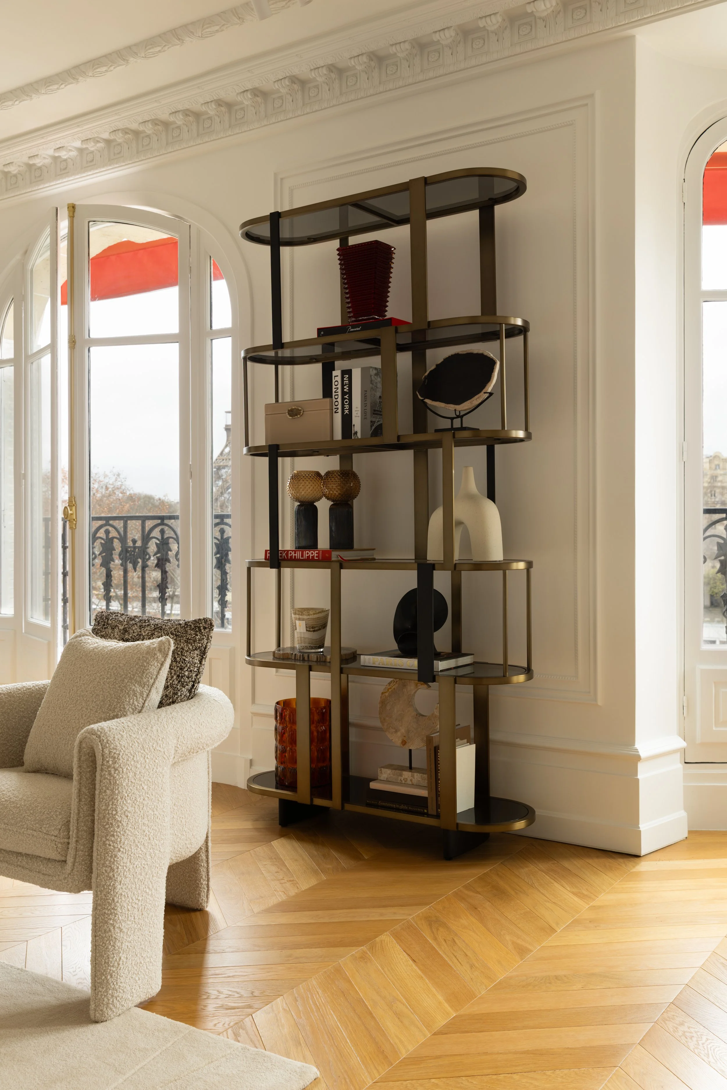 Coin salon avec étagère décorative et fauteuil texturé, décoration intérieure élégante avenue de New York à Paris.