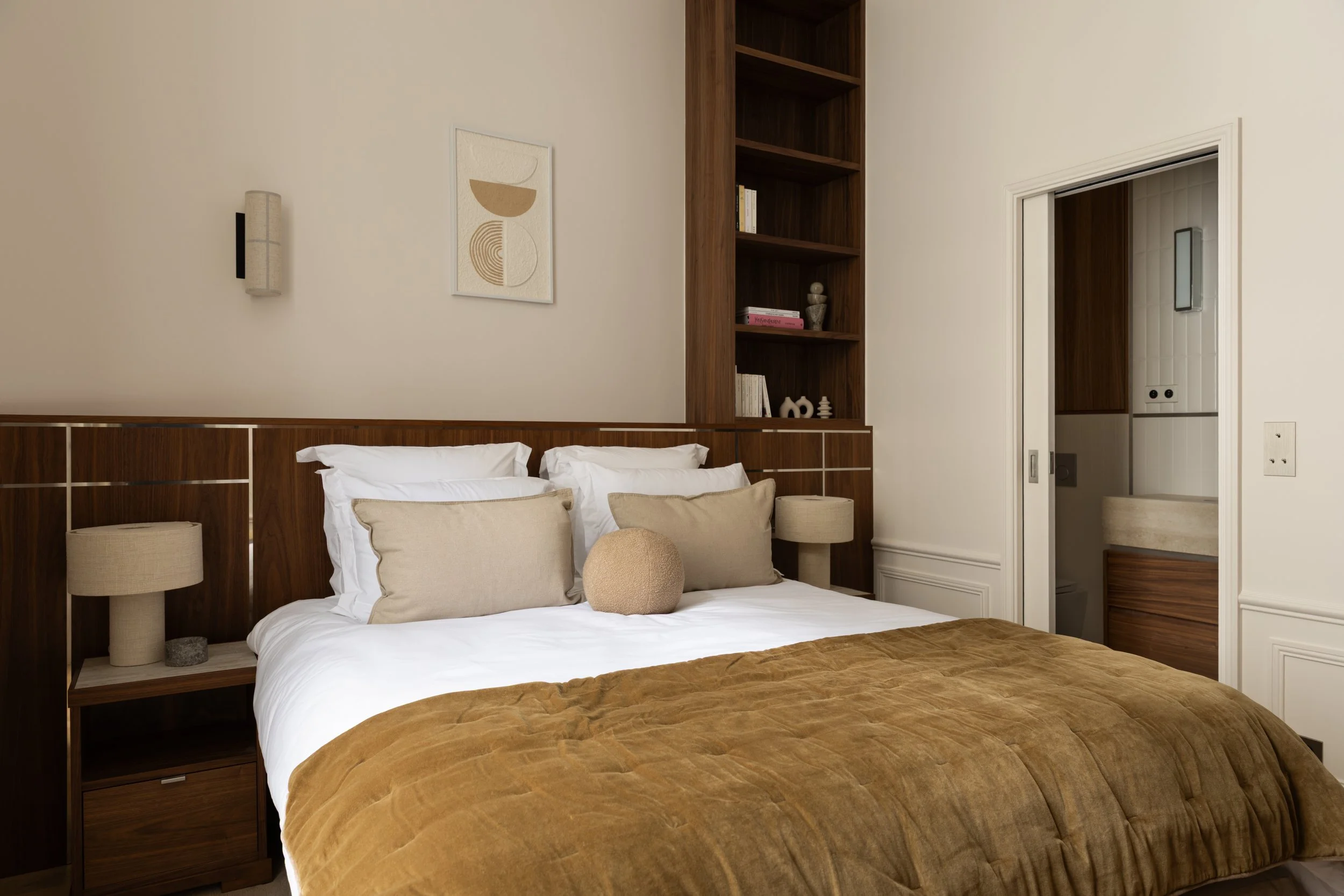 Chambre haut de gamme à Paris avec tête de lit en bois sur mesure, bibliothèque intégrée et salle de bains attenante – Intérieurs Chomet.