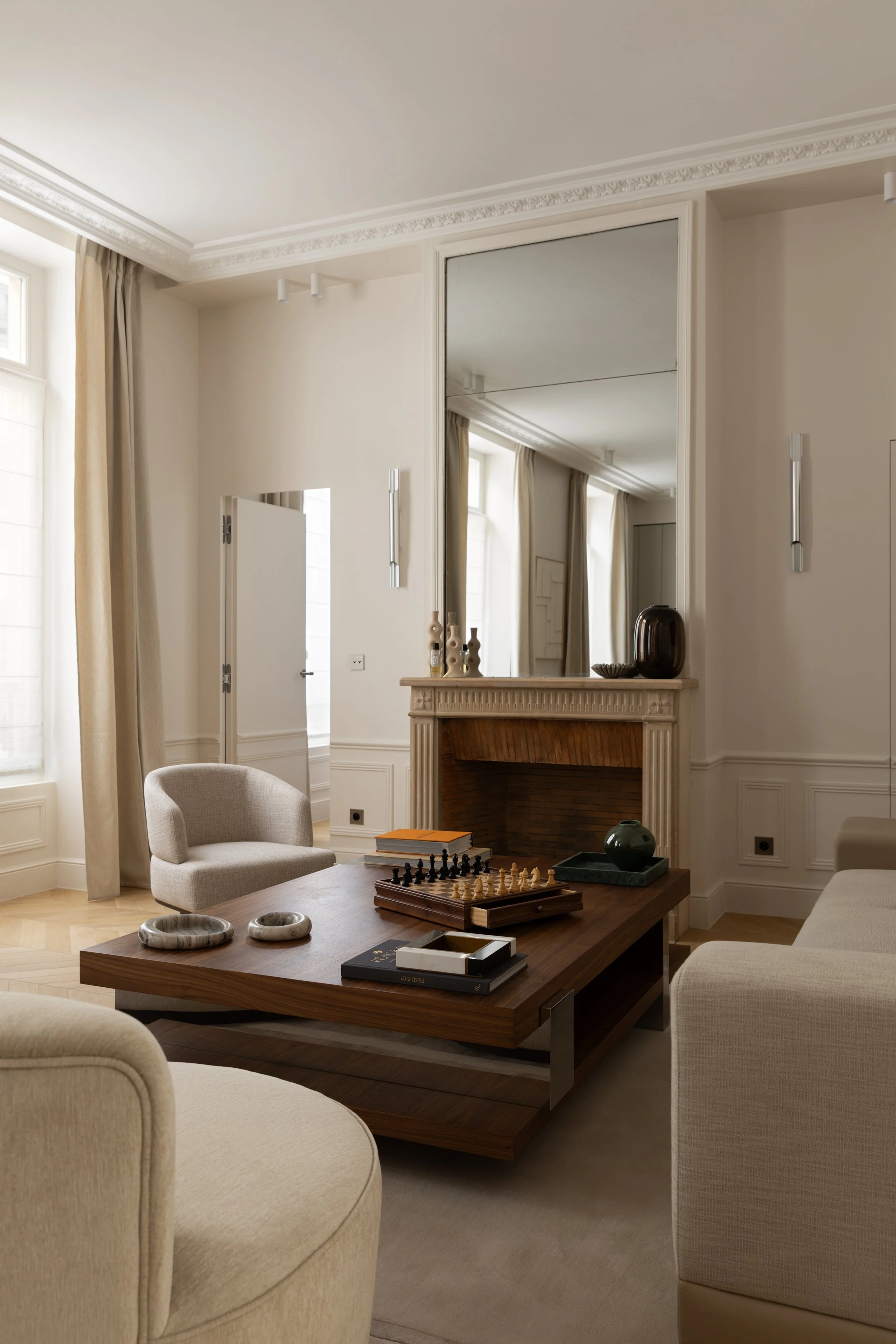 Rénovation d'un salon haussmannien à Paris avec cheminée ancienne, grand miroir, moulures et mobilier contemporain – Intérieurs Chomet.