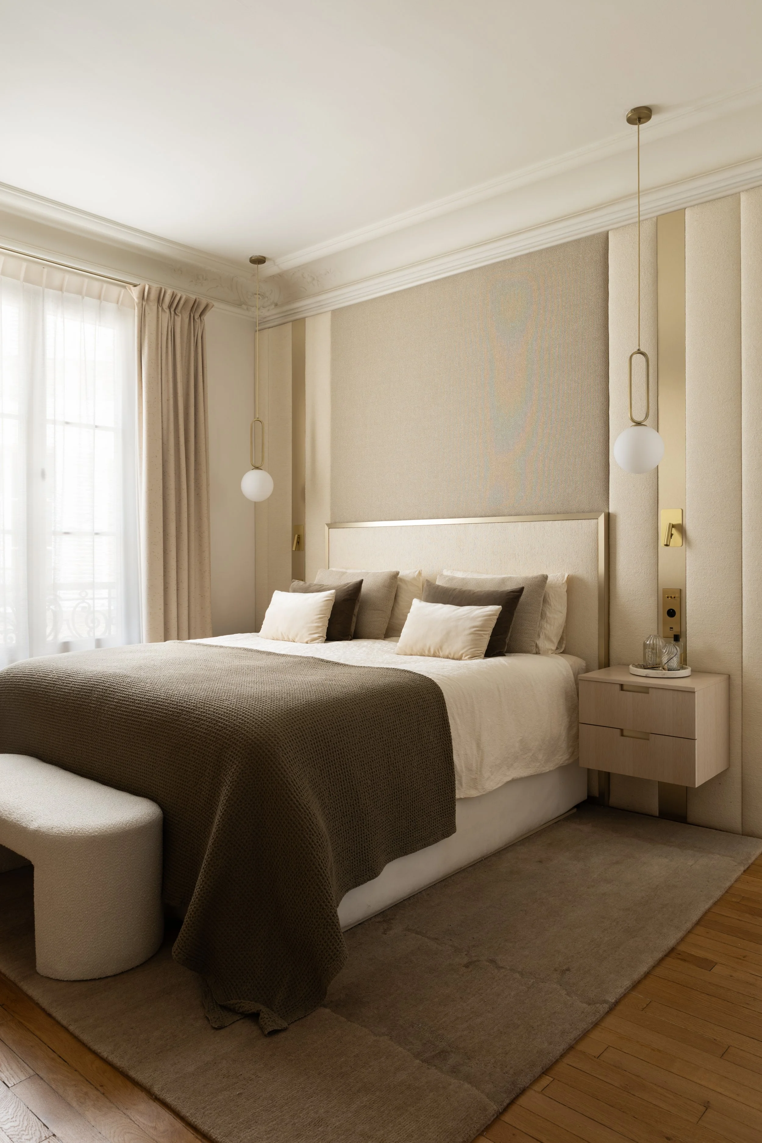Chambre parentale du projet Malesherbes à Paris, avec tête de lit tapissée beige, chevets suspendus en bois clair et suspensions à globes blancs et détails dorés — Intérieurs Chomet.