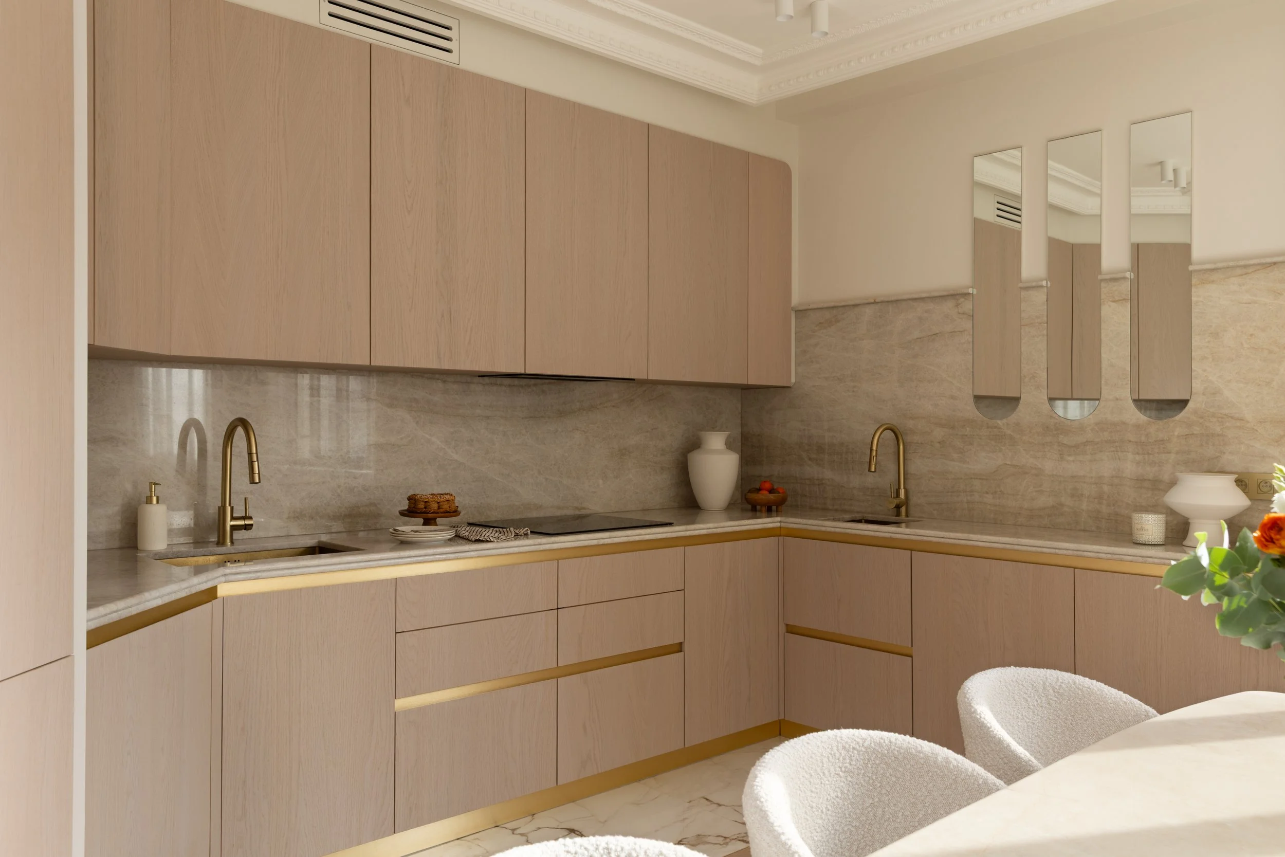 Cuisine d’angle sur mesure en bois clair, crédence minérale et design épuré.