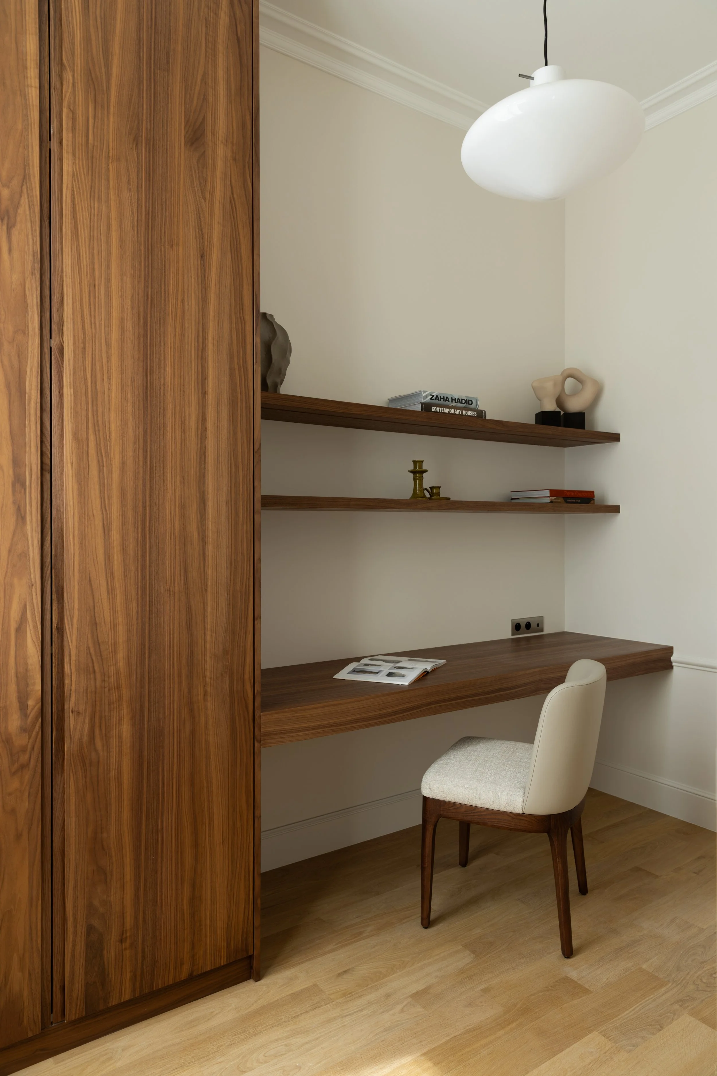 Aménagement d'un bureau sur mesure à Paris avec plan de travail en bois, étagères murales et rangements intégrés – Intérieurs Chomet.