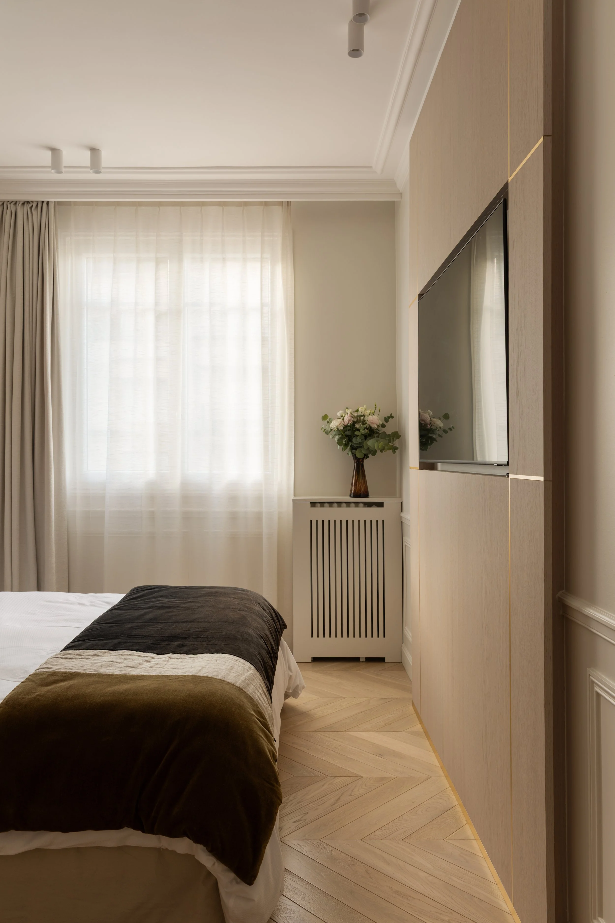 Chambre lumineuse avec rideaux en lin naturel, habillage mural réalisé sur mesure comme un cadre tout hauteur pour la TV