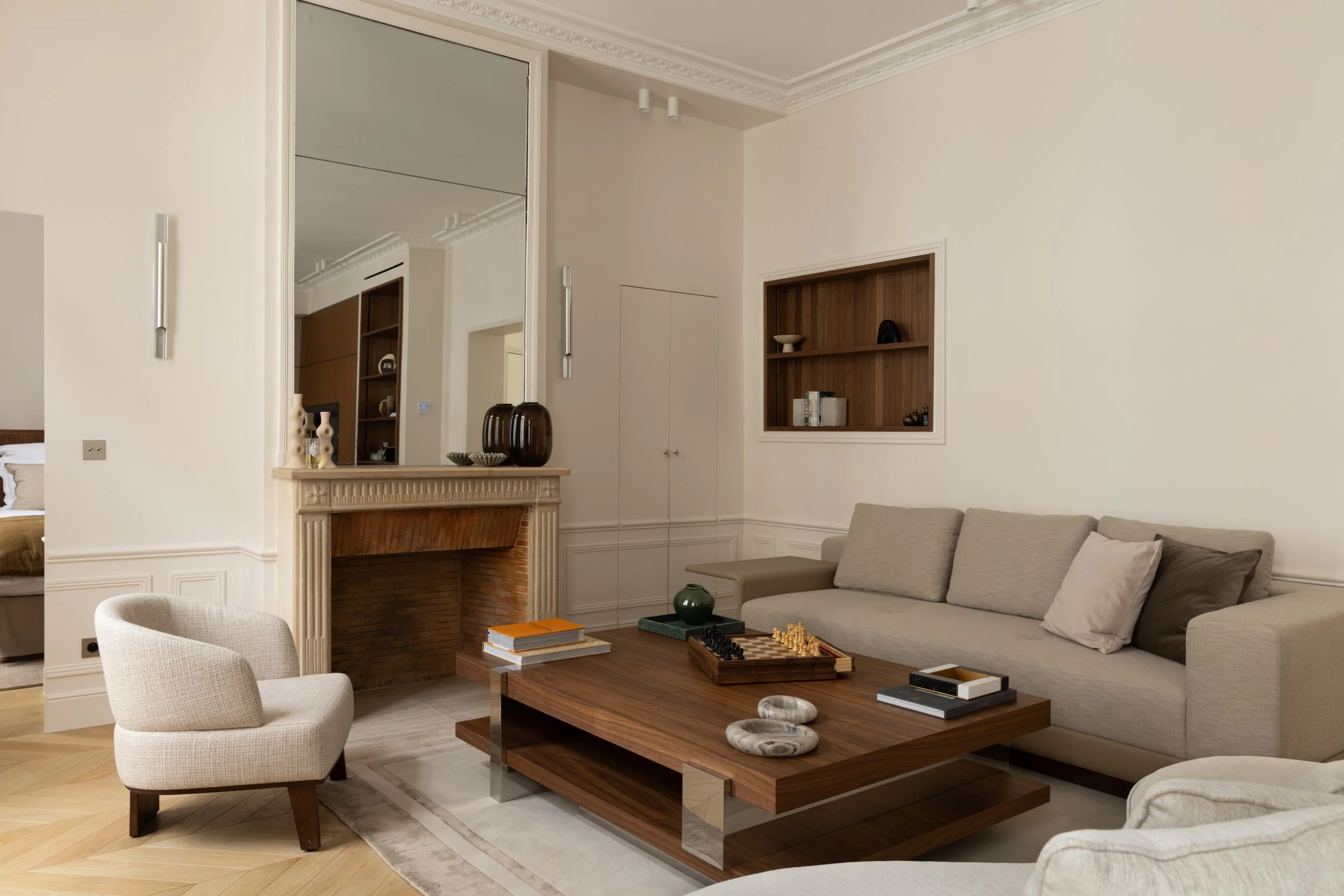 Salon haussmannien rénové à Paris avec cheminée ancienne, moulures, canapé contemporain et mobilier en bois – Architecture d'intérieur Intérieurs Chomet.