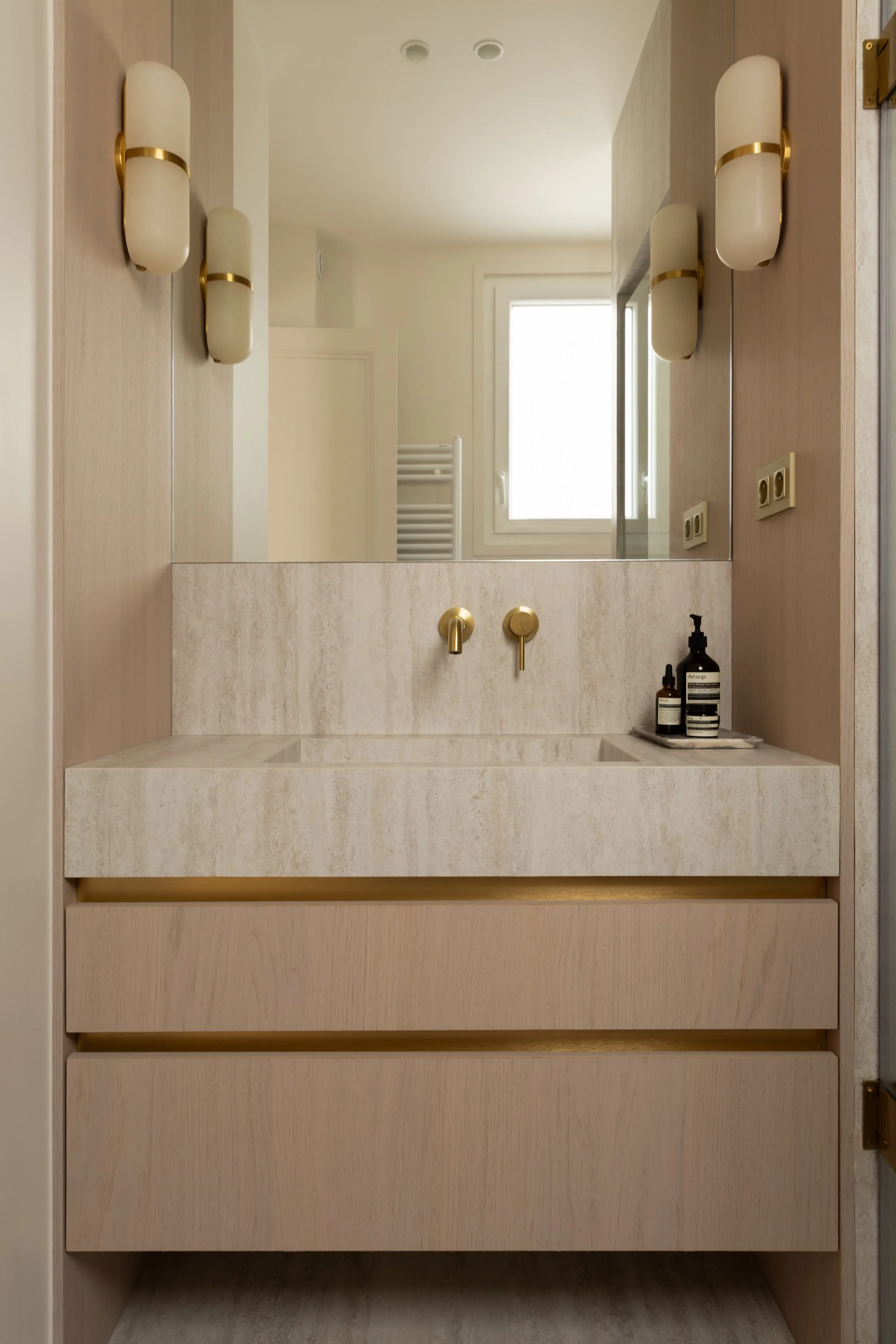 Salle de bain master en travertin
Salle de bain contemporaine avec vasque en pierre naturelle et robinetterie dorée.